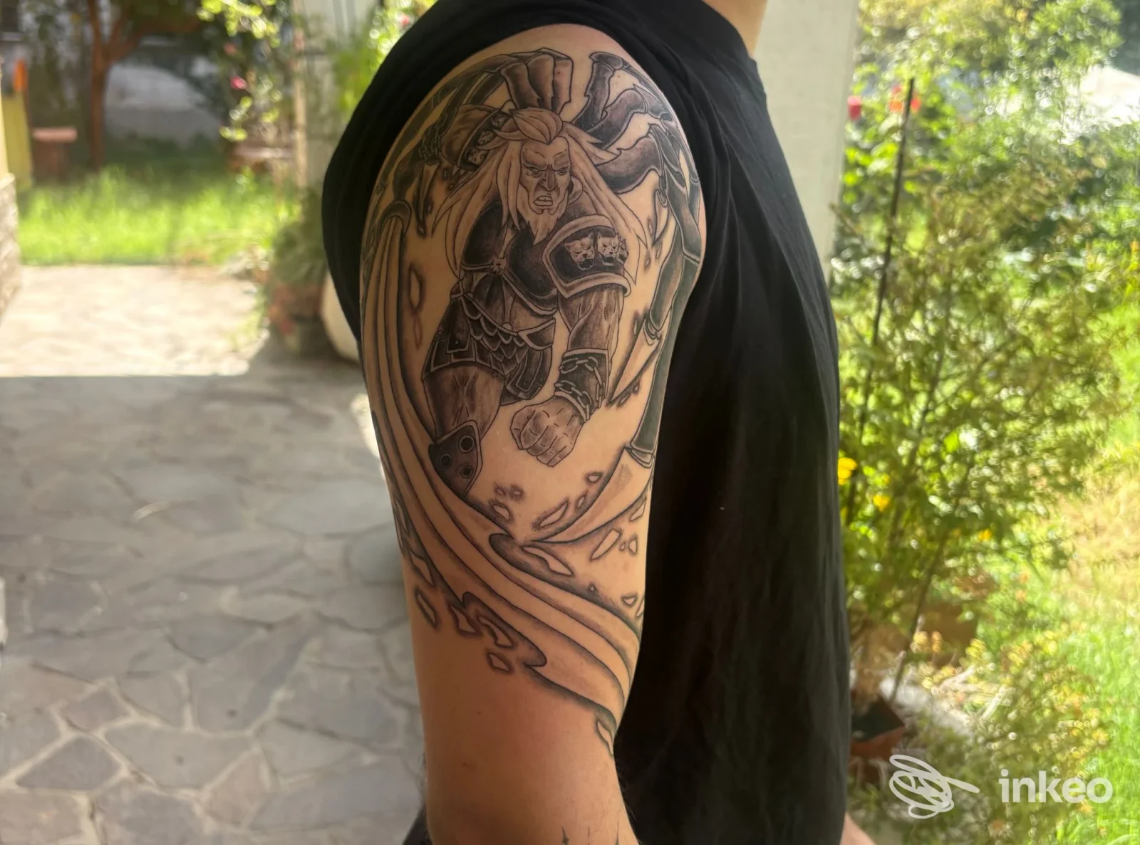Tatuaggio in bianco e nero sul braccio superiore, scatto all'aperto per PhiStudio Udine Tattoo a Udine.