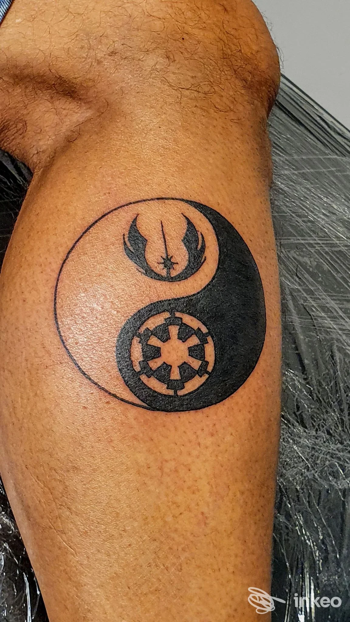 Tatuaggio yin-yang stilizzato sul braccio: simboli di Ribelli e Impero. Nero Argento a Different Shop - Tattoo & Piercing, Cordenons.