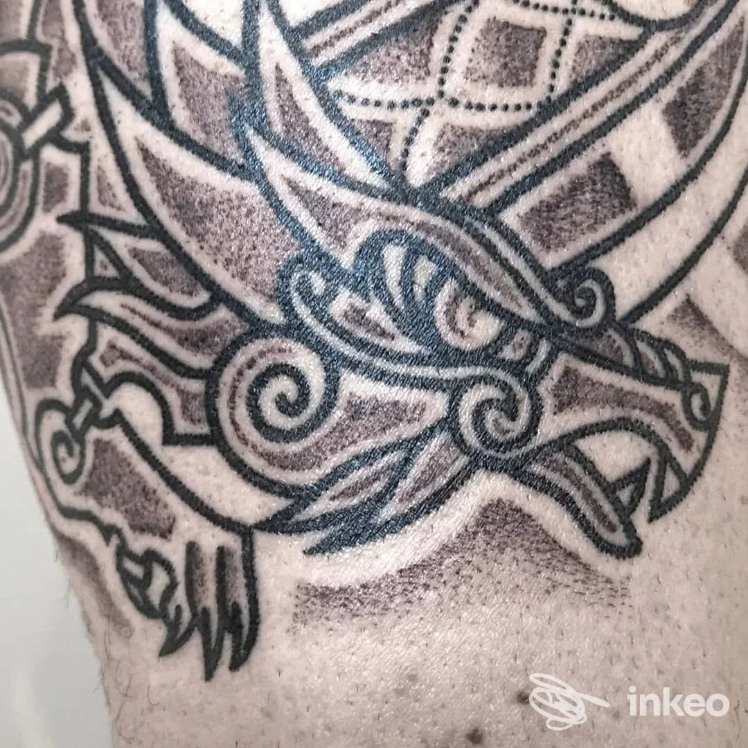 Particolare di un tatuaggio su pelle umana: una spada decorata con impugnatura ornata. Primo piano, senza volto visibile, su tessuti cutanei.