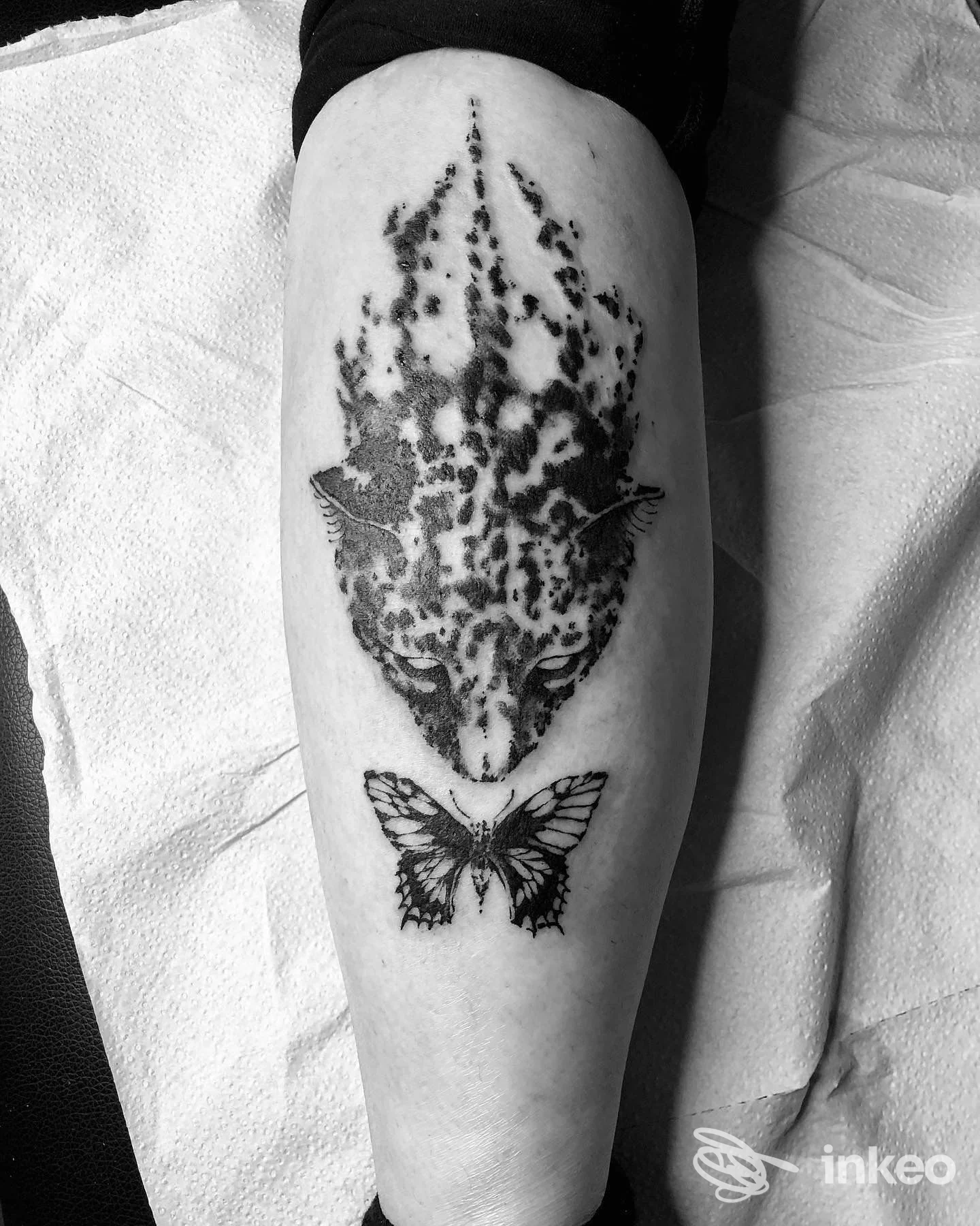 Tatuaggi in bianco e nero su polpaccio: volto stilizzato maculato e farfalla. Needless Tattoo Studio, Udine.