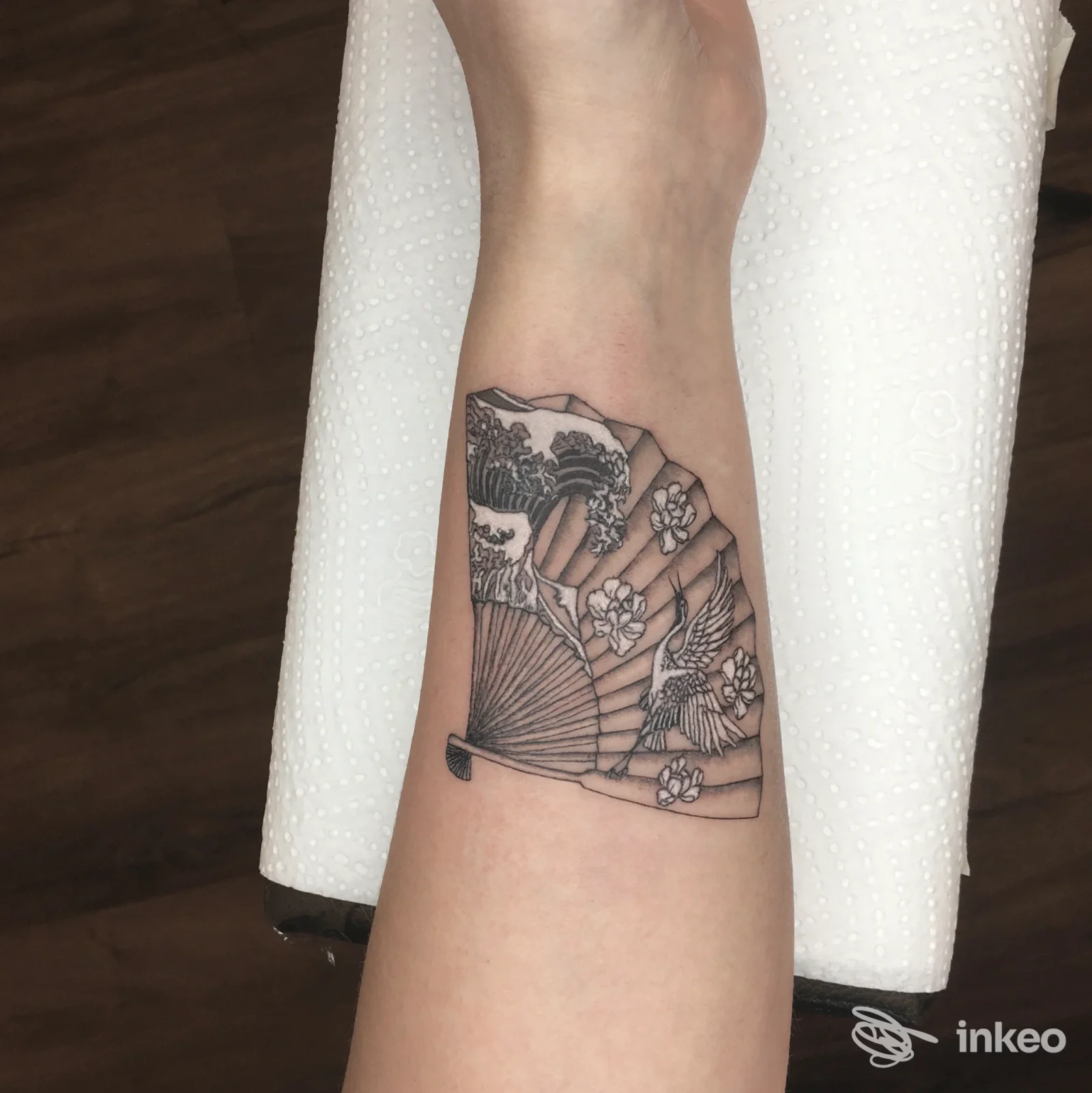 Tatuaggio su avambraccio a ventaglio con gru e fiori, fotografia condivisa da Eremo Studio, Pordenone.