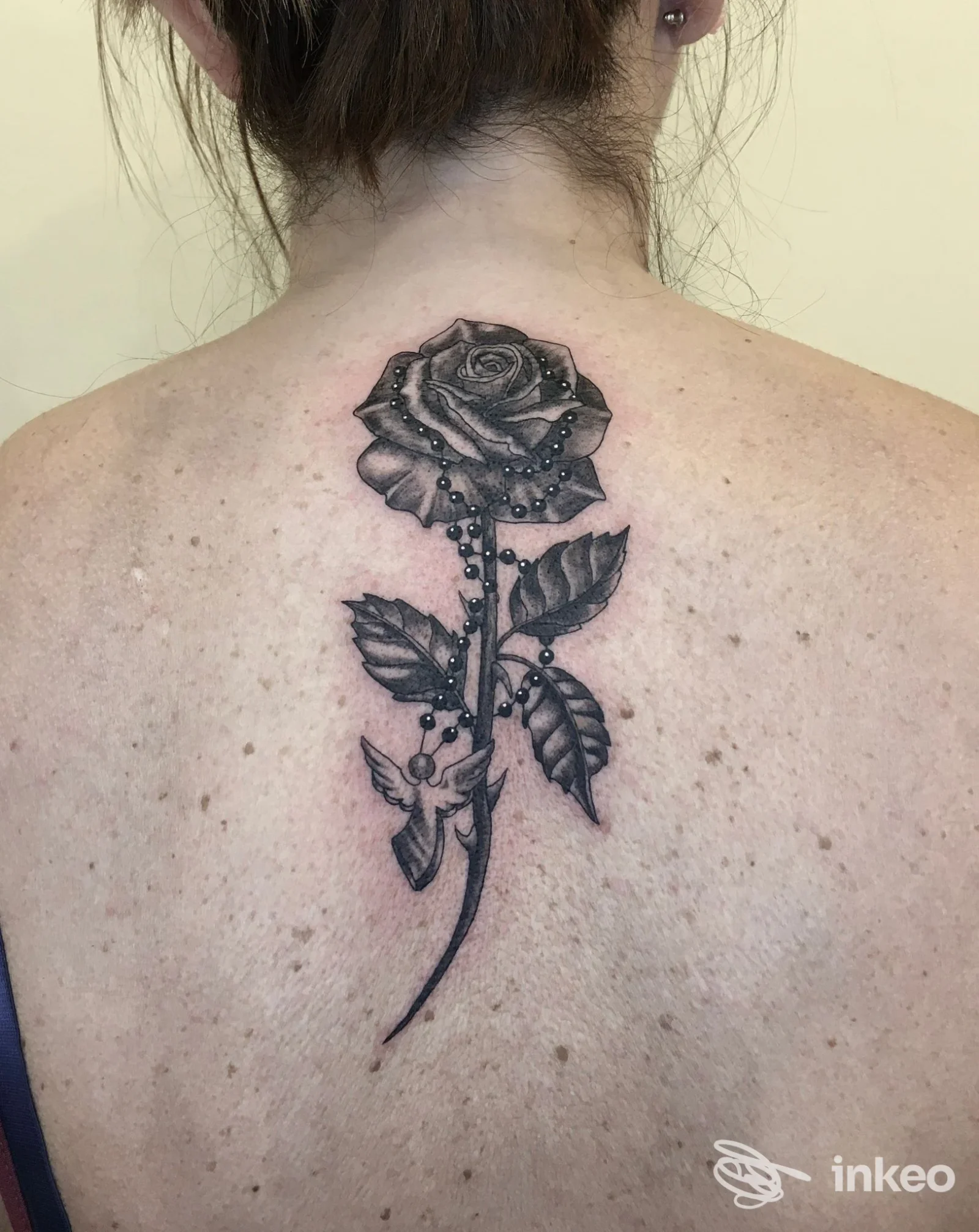Tatuaggio a rosa in bianco e nero sulla parte alta della schiena, foto fornita da Eremo Studio a Pordenone.