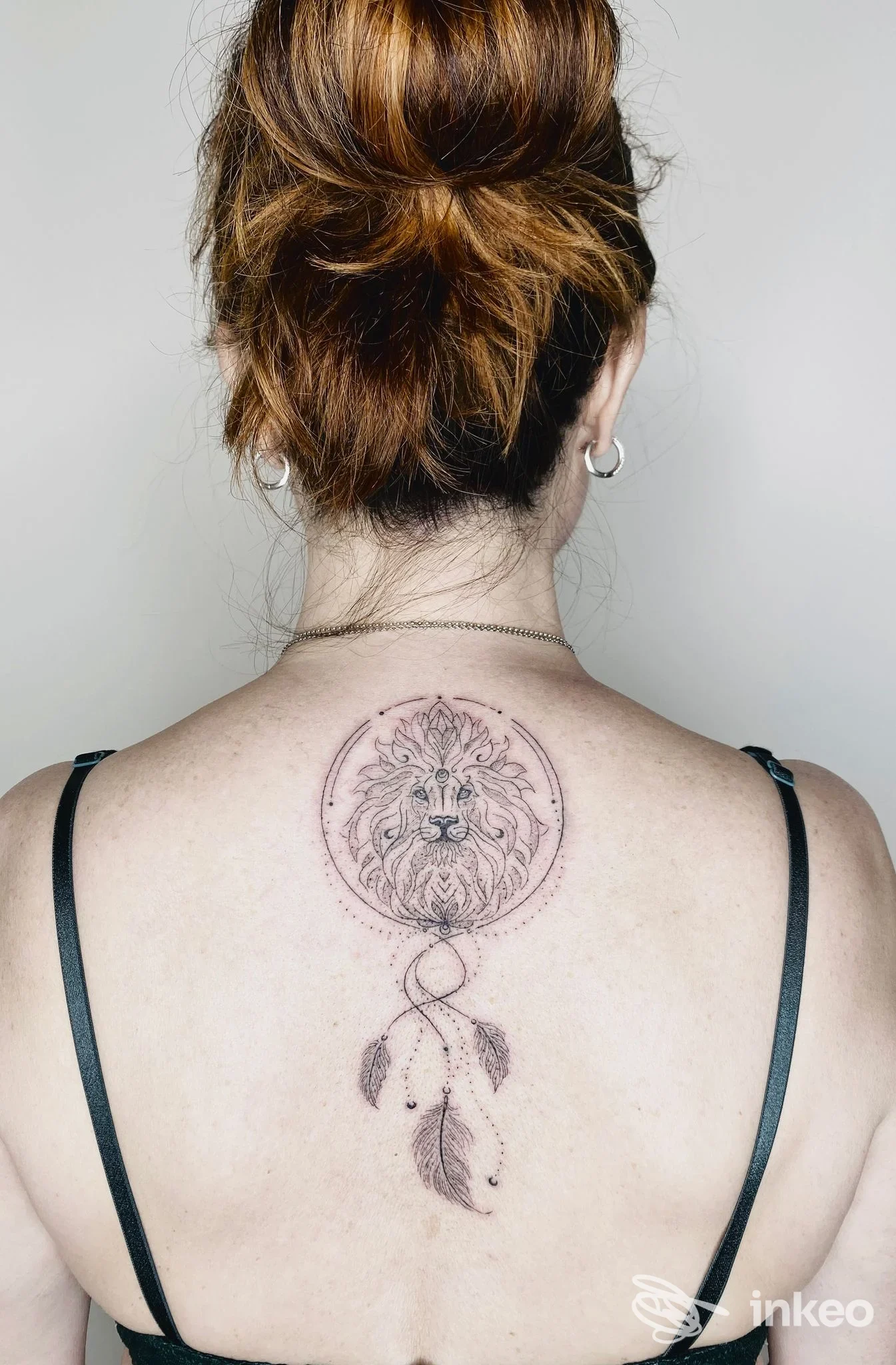 Tatuaggio sulla parte superiore della schiena con volto di leone in stile linework e piume, foto per Giovanna Bacchin, Udine.