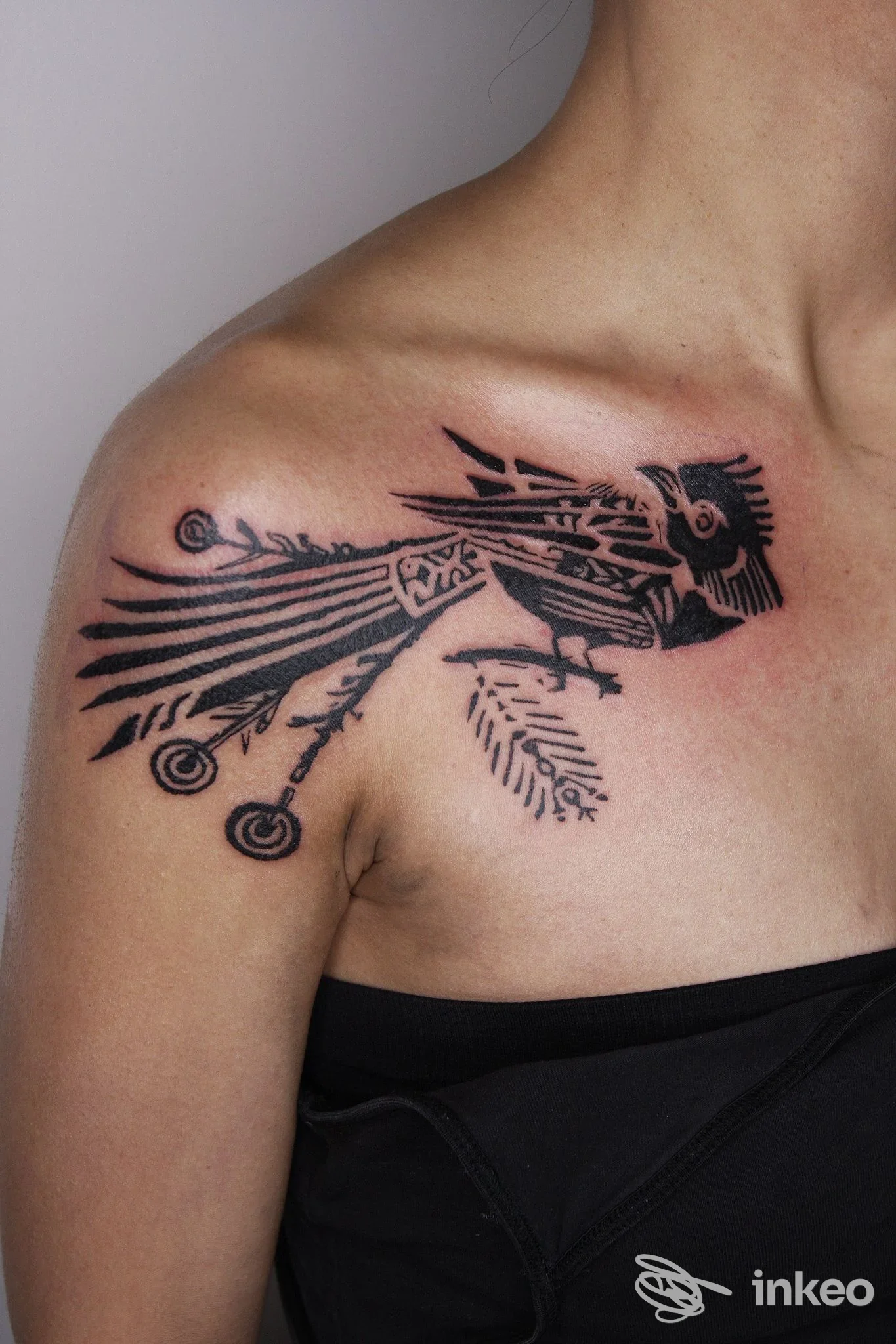 Tatuaggio nero stilizzato a forma di uccello sulla spalla, New Nazareth Tattoo Studio, Udine.