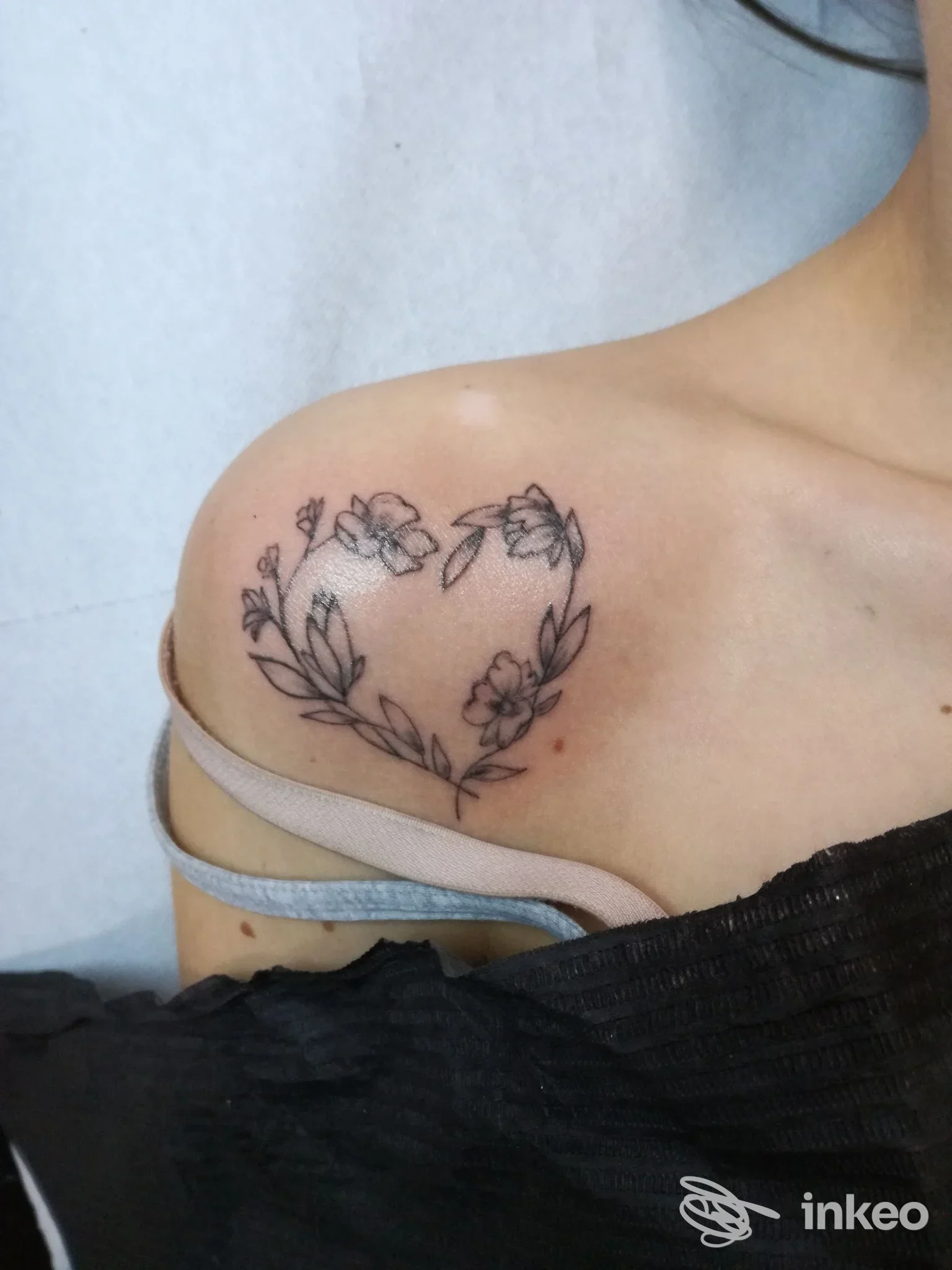 Tatuaggio floreale a forma di cuore sulla clavicola, eseguito da Jolie Tattoo Piercing Estetica a Udine.
