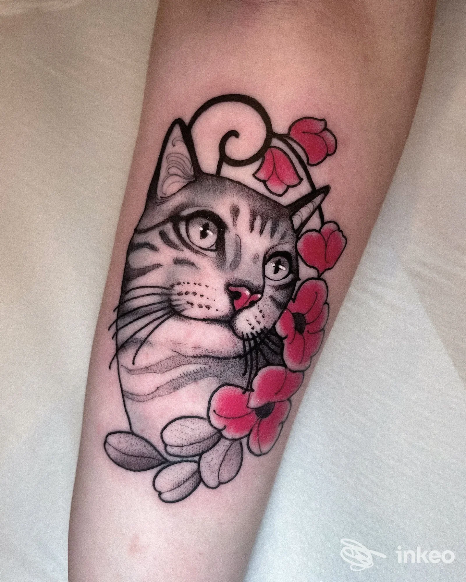 Tatuaggio su avambraccio: volto di gatto stilizzato con fiori rosa; immagine fornita da PERSEVERA TATTOO SHOP, Gorizia.