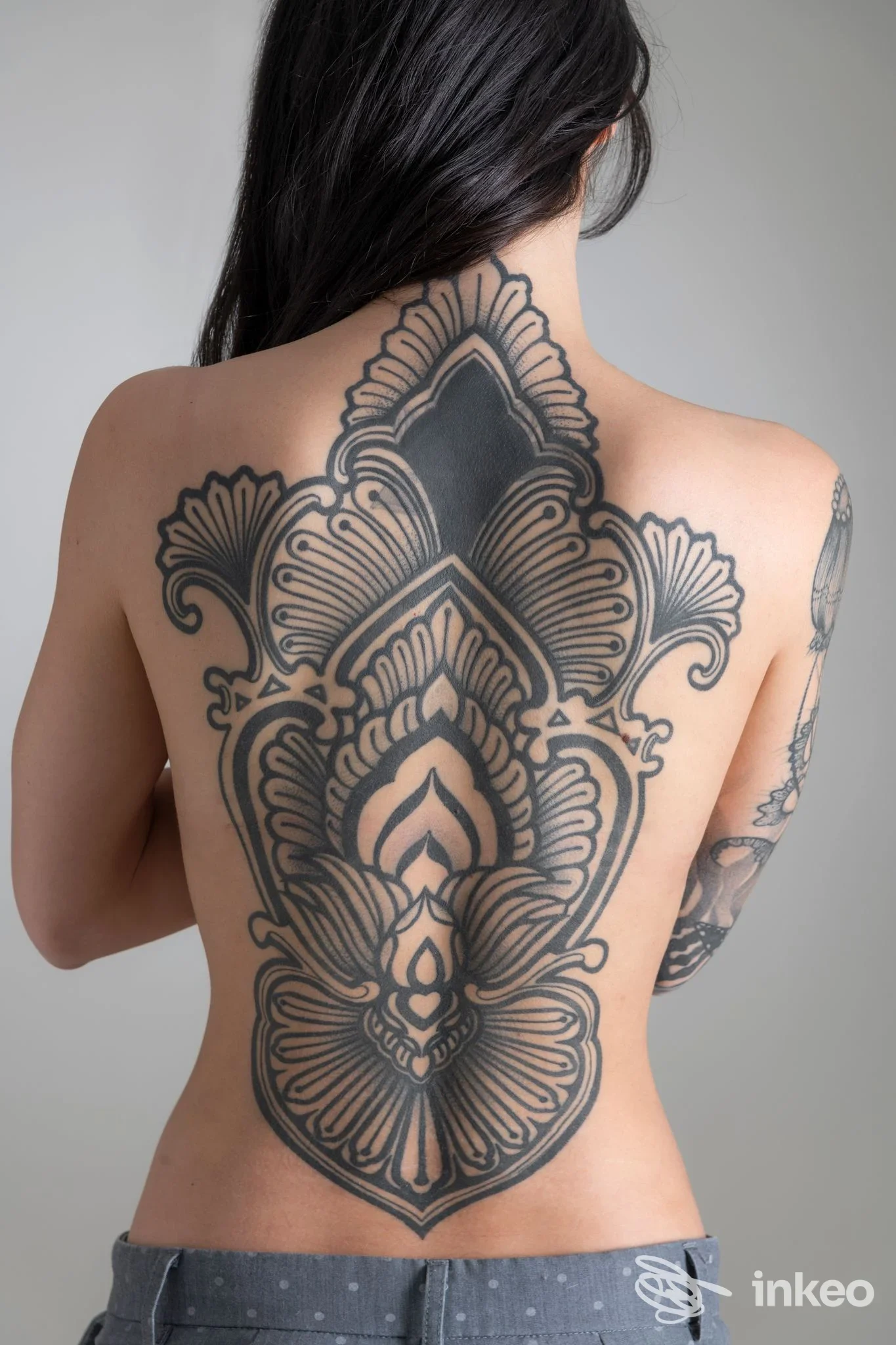Grande tatuaggio ornamentale nero che copre la schiena di una donna fotografata in studio. Le Tatuarti, Pordenone.
