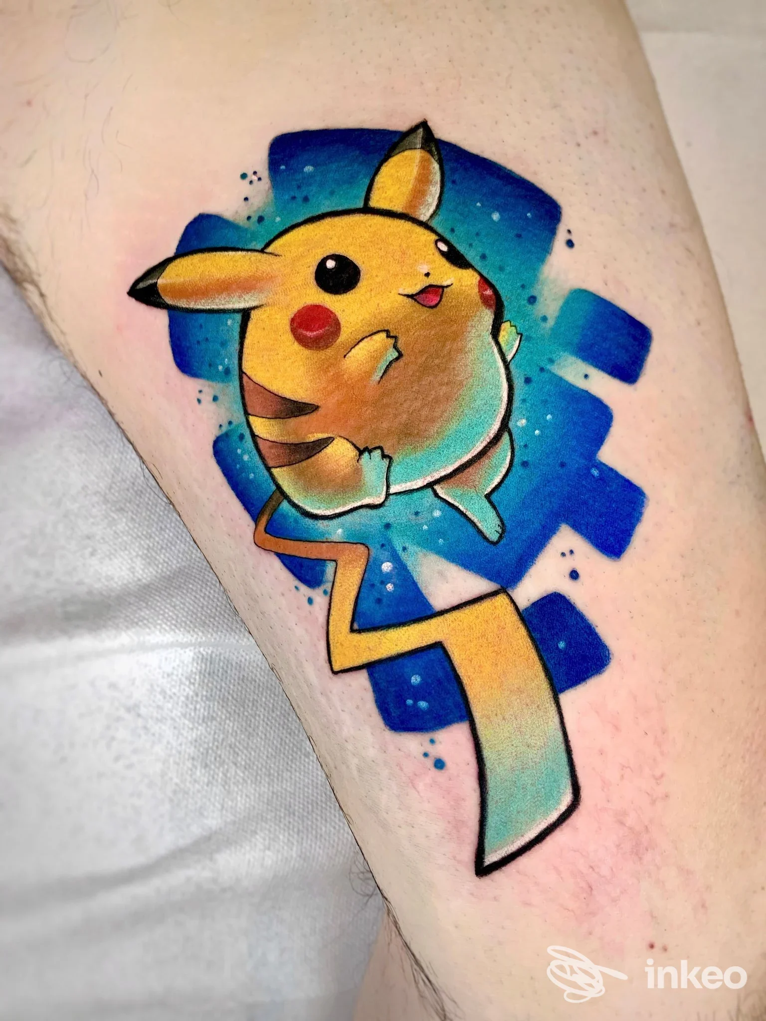 Tatuaggio colorato di Pikachu sul braccio, lavoro eseguito da Le Tatuarti a Pordenone, sfondo blu stellato.