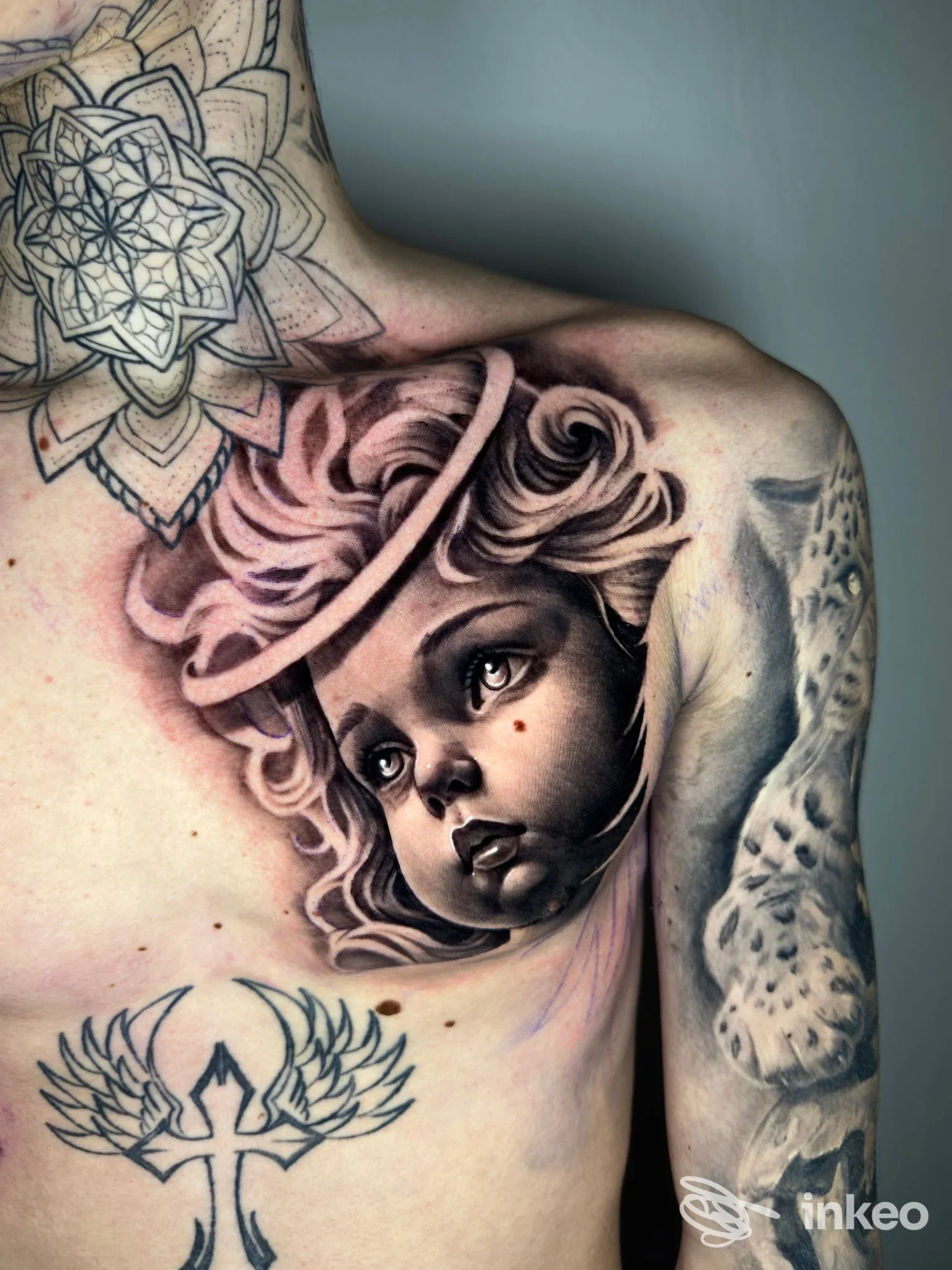 Tatuaggio realistico in bianco e nero sul petto e spalla, ritratto infantile e mandala. Sorry Mama Tattoo & Piercing, San Giorgio di Nogaro.