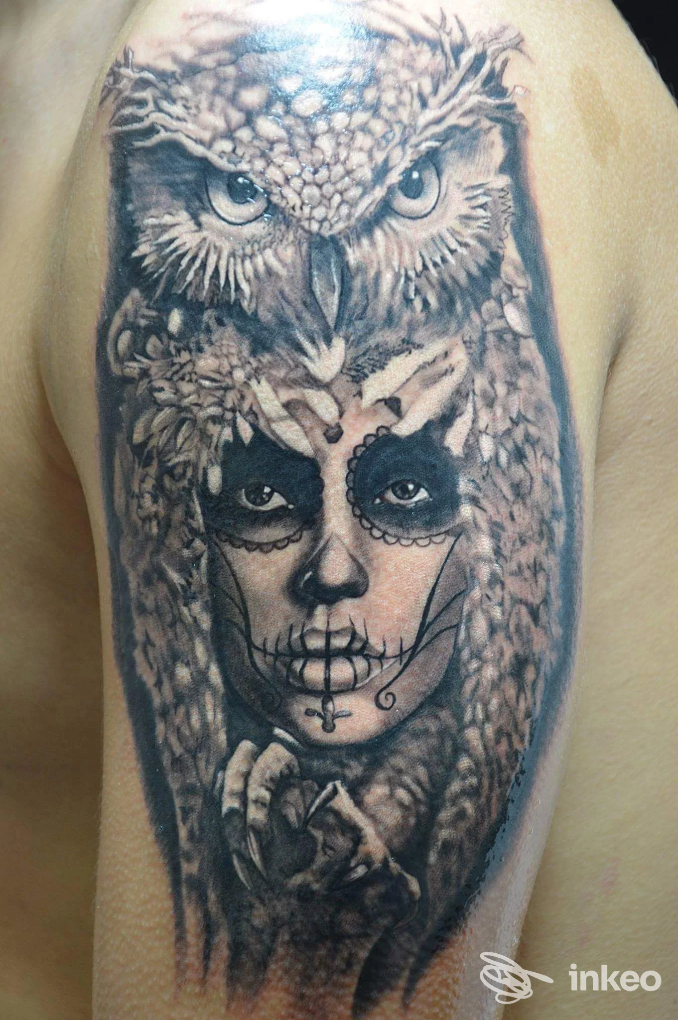 Tatuaggio realistico su braccio superiore con gufo sovrastante e volto in stile sugar skull, Gabriel's Tattoo Studio, Udine.