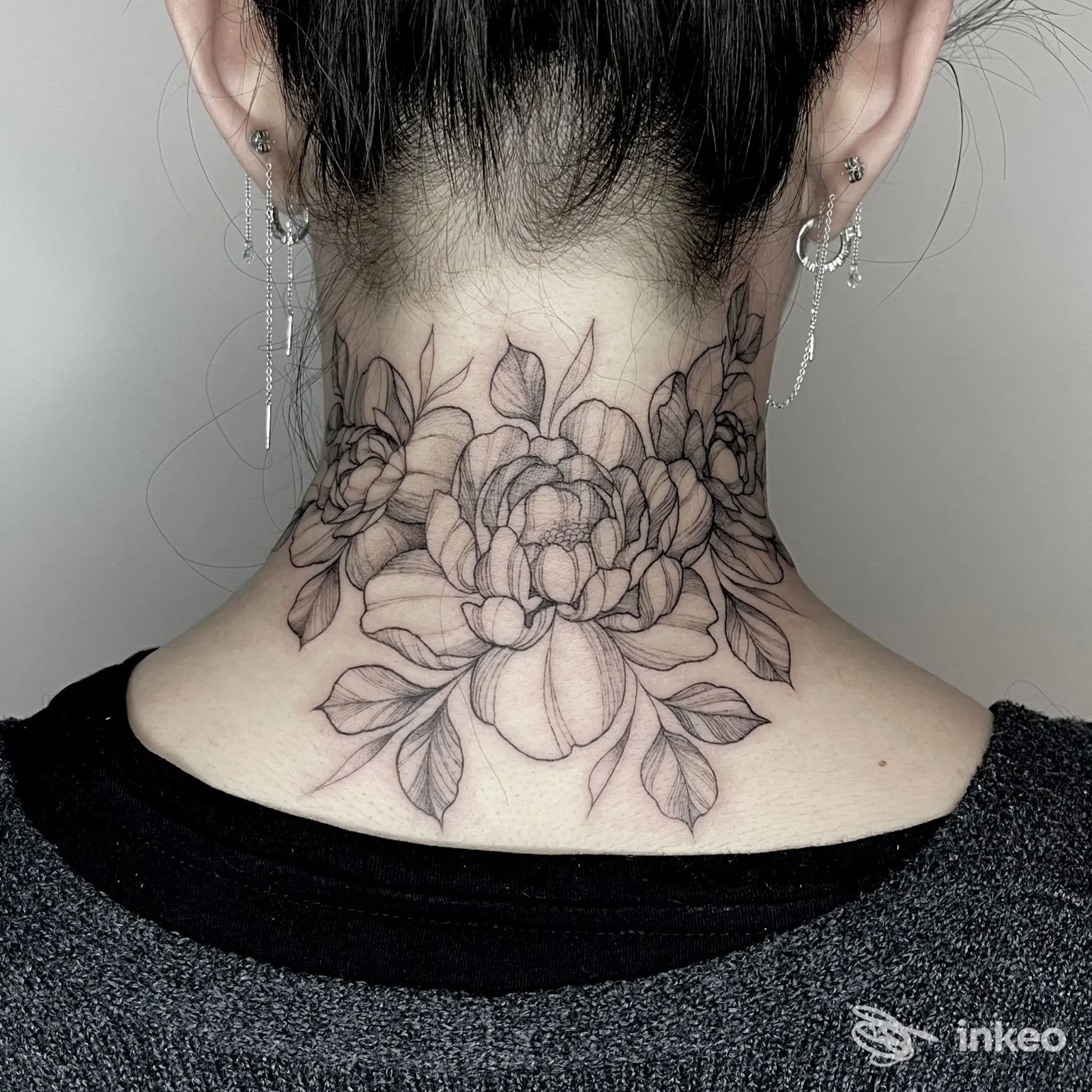 Grande tatuaggio floreale in bianco e nero sulla nuca, realizzato da Ink Blooms Tattoo Studio a Udine, linework delicato e sfumature leggere.
