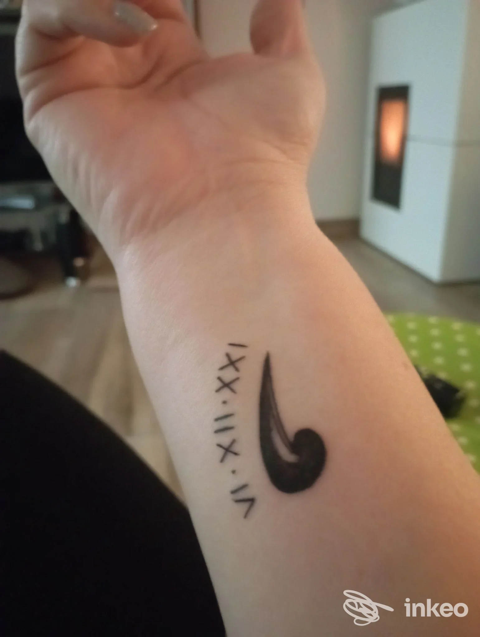 Primo piano di un tatuaggio sul polso interno con un motivo nero a goccia e numeri romani. Tiki Tattoo, Gorizia.