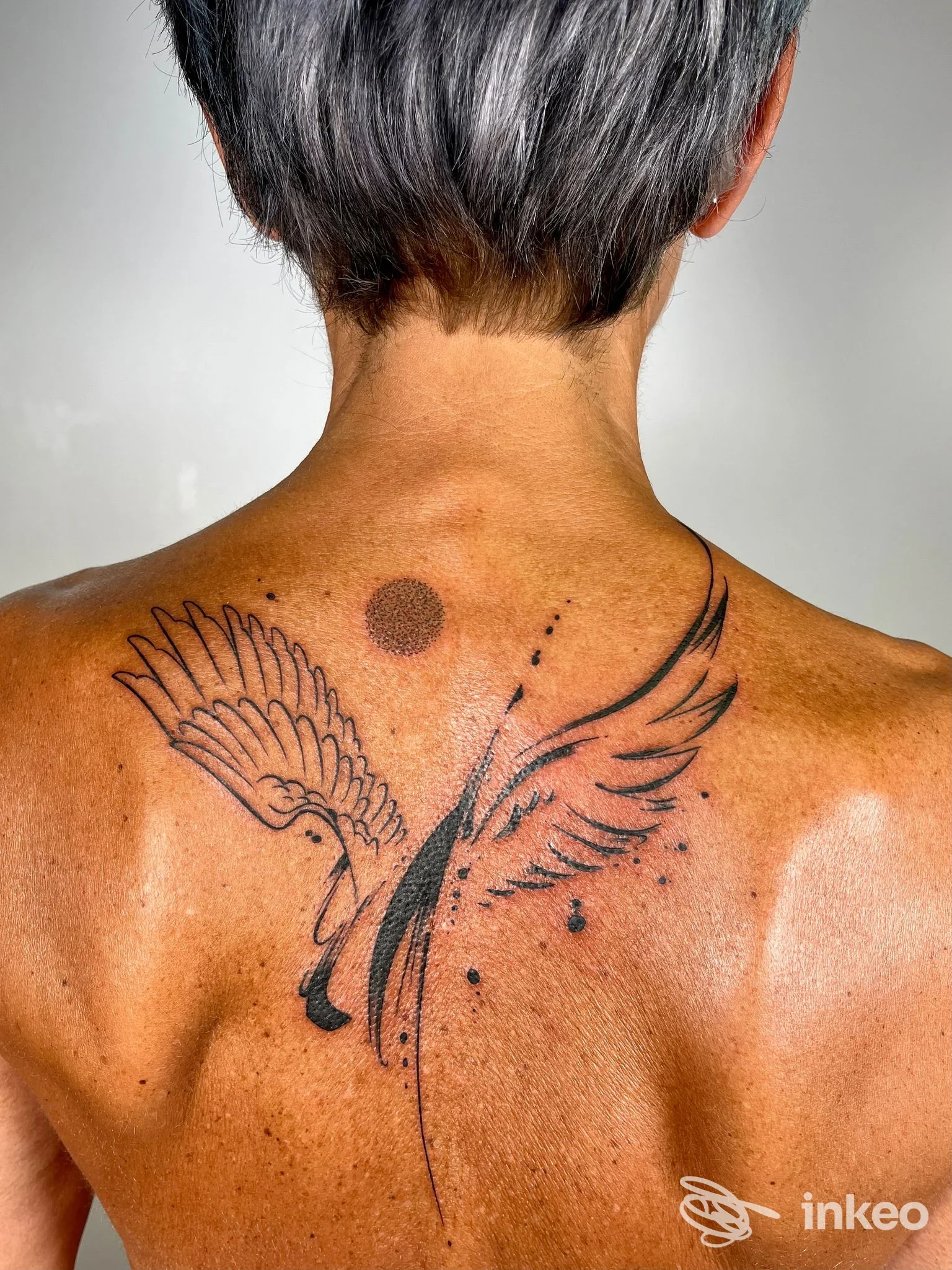 Tatuaggio a ali stilizzate sul dorso superiore, fotografia realizzata per Luca Braidotti Tattoo Studio a Udine.