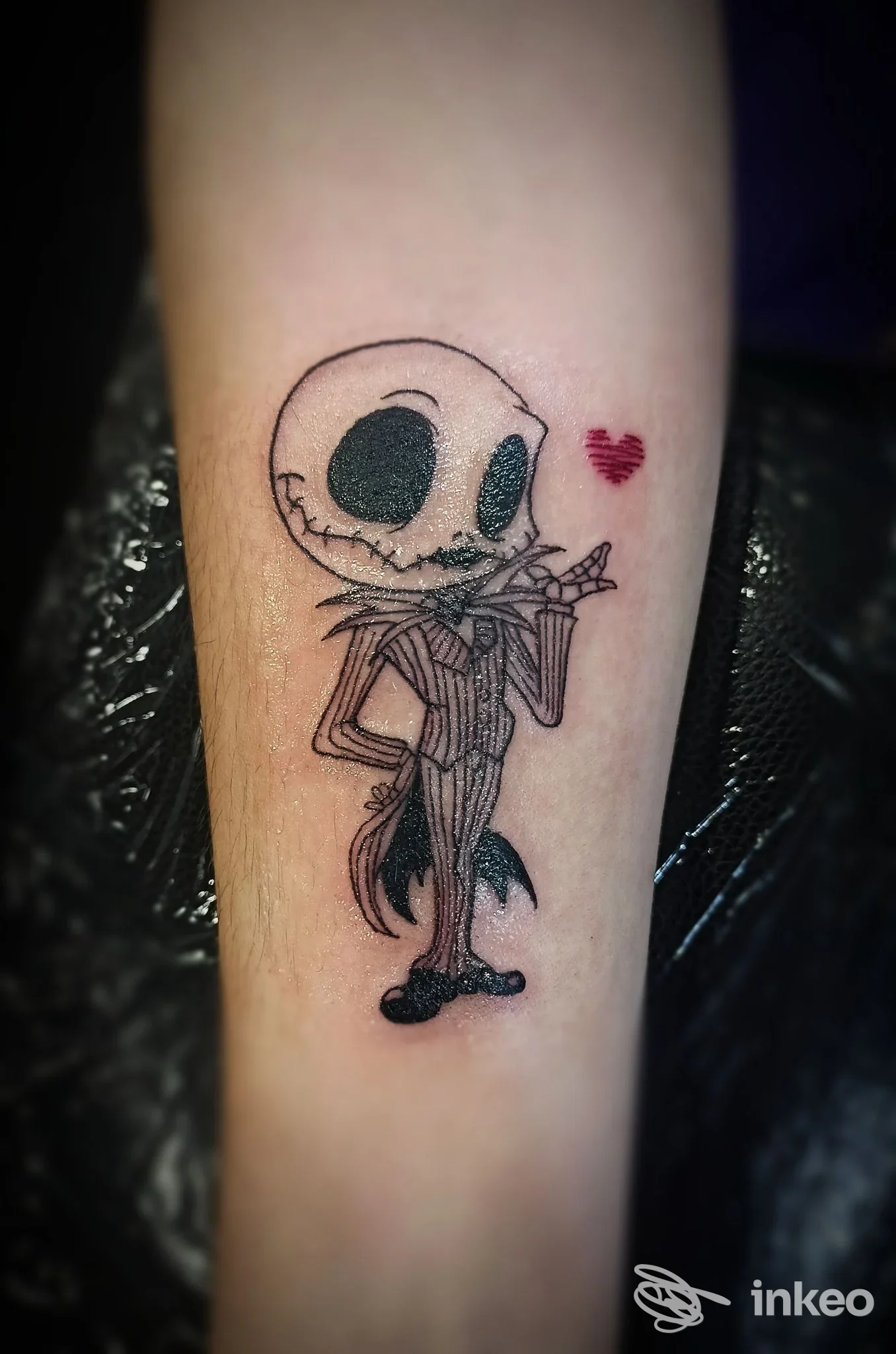 Tatuaggio su avambraccio raffigurante un personaggio stilizzato in bianco e nero e un piccolo cuore rosso. Sweetie Tattoo Studio, Rive d'Arcano.