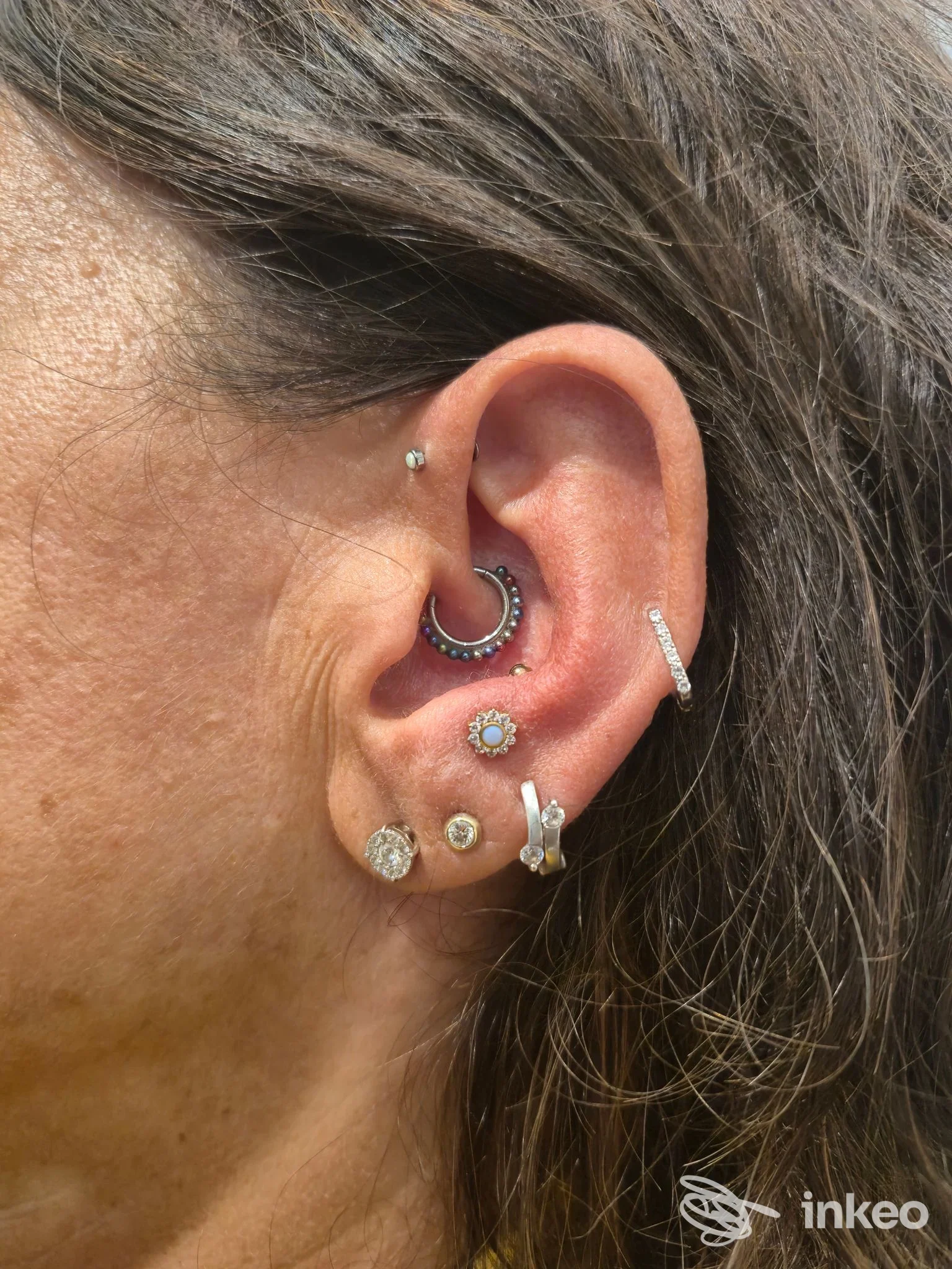 Primo piano di orecchio con più piercing realizzati da Luxury Body Piercing a Trieste, dettagli dei gioielli e del lobo.