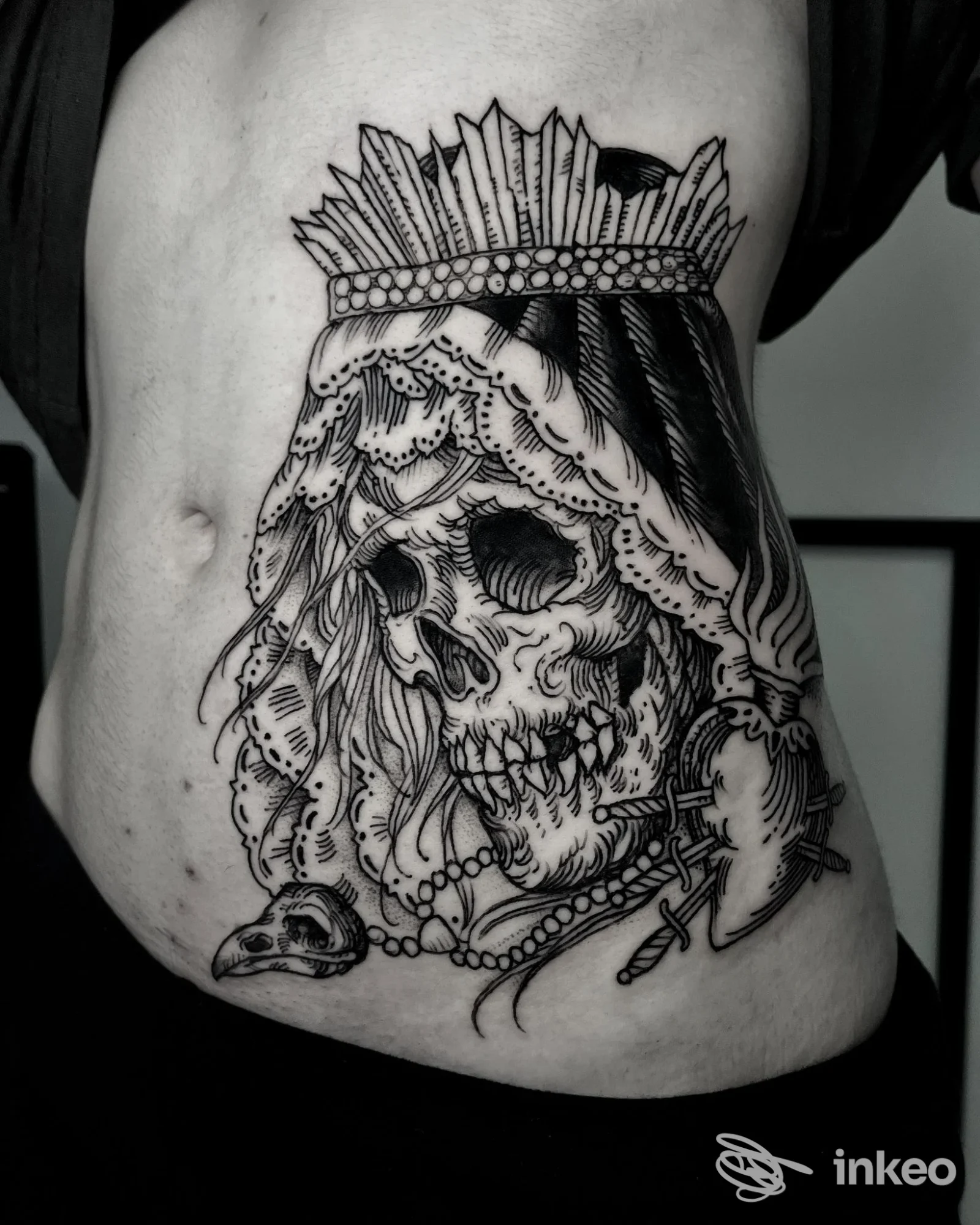Grande tatuaggio blackwork su fianco con un teschio coronato, velo e perle, realizzato da ColdStreet a Udine su pelle reale.