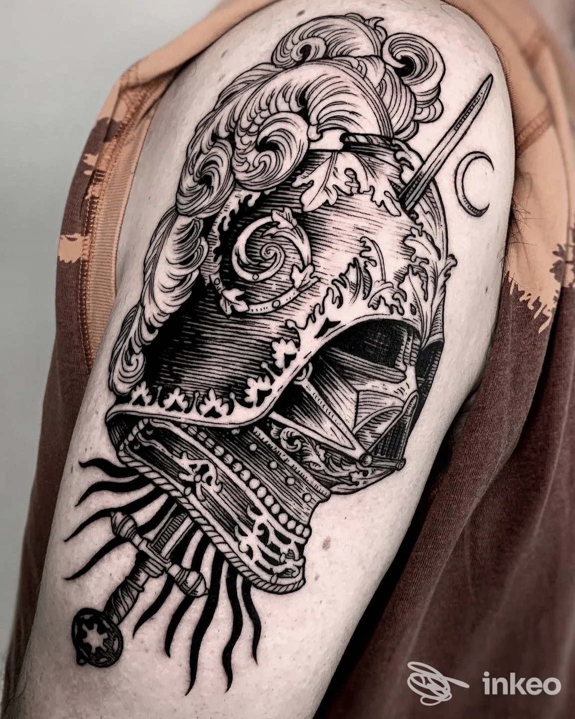 Grande tatuaggio a elmo ornamentale sul braccio superiore, foto fornita dallo studio ColdStreet a Udine.