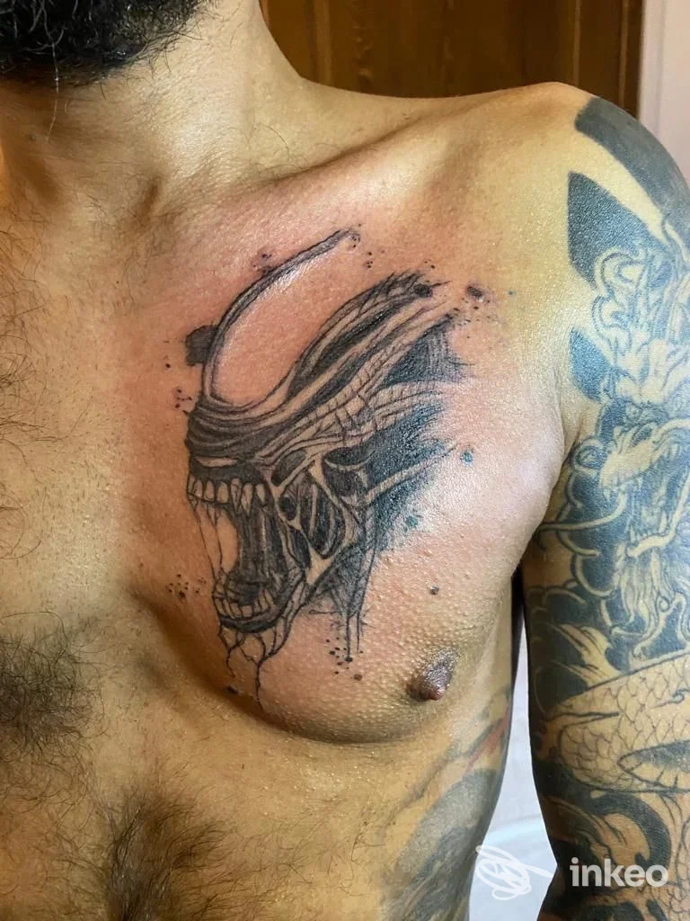 Primo piano del tatuaggio a petto realizzato da Magia Nera tattoo a Venzone, creatura stilizzata in nero su pelle maschile.