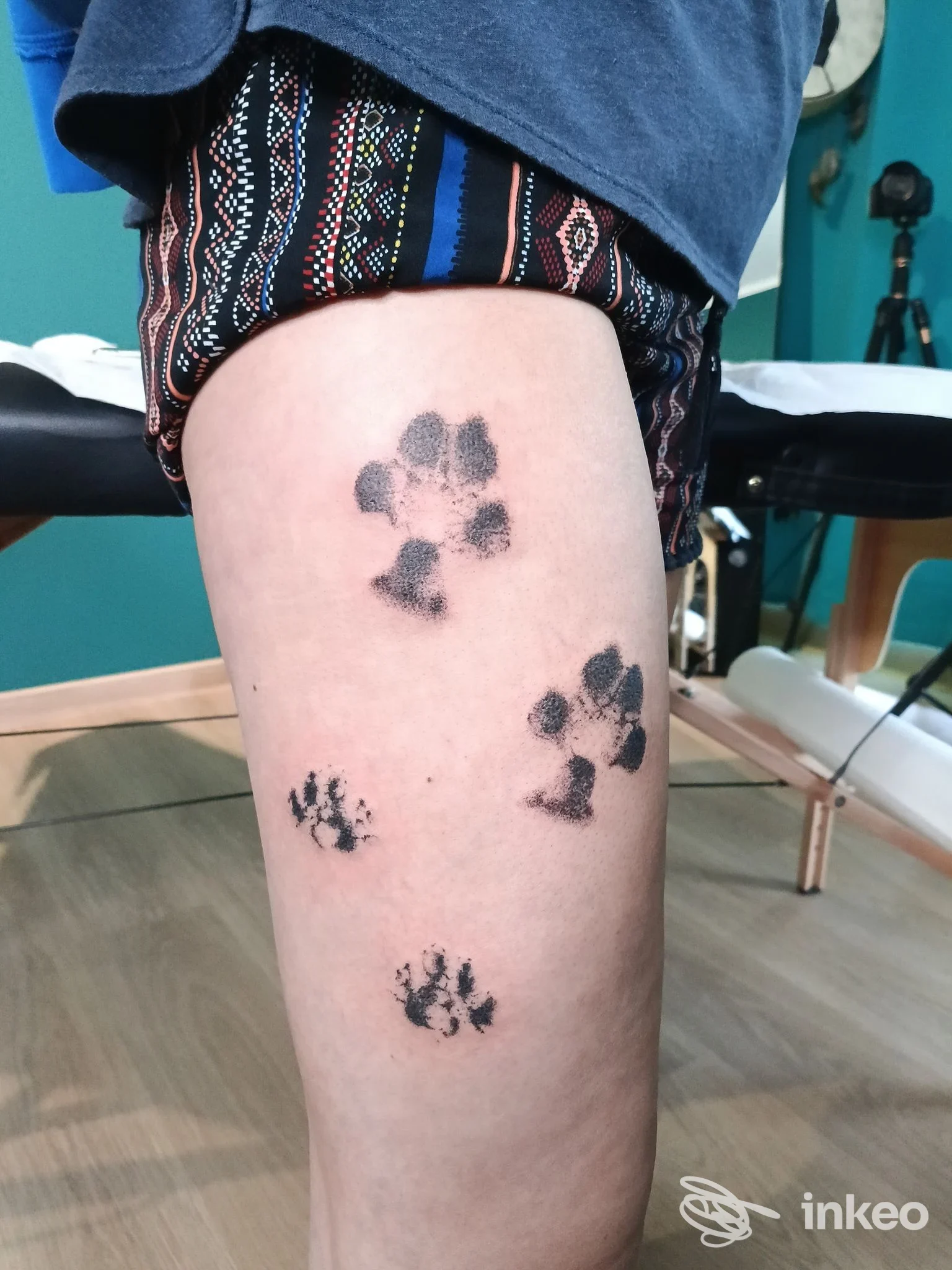 Quattro impronte di zampe tatuate in nero sulla coscia, foto scattata nello studio Ragnarok handpoke ritual tattoo studio a San Giovanni.