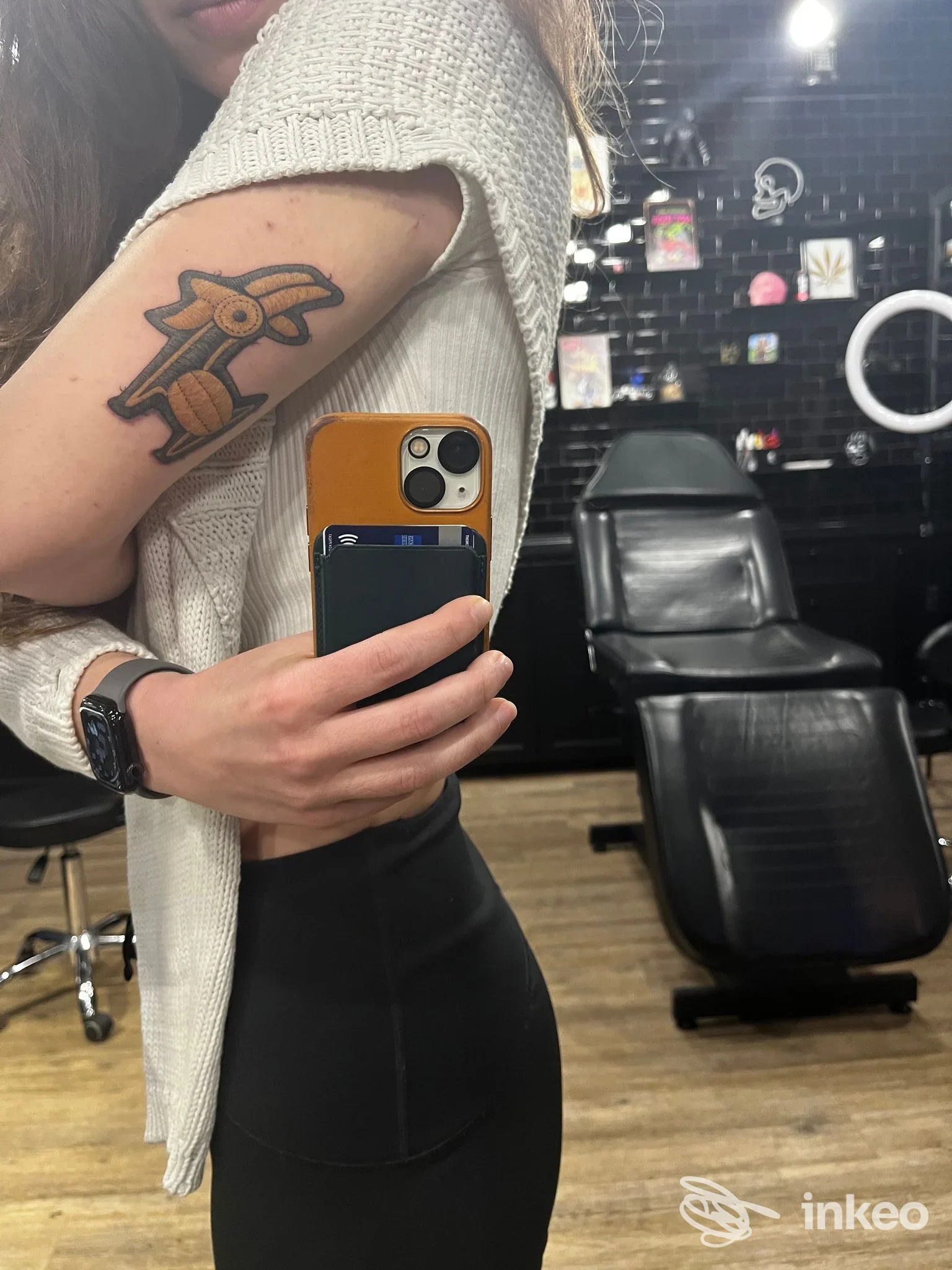 Tatuaggio raffigurante una tartaruga sulla pelle del braccio di una persona in uno studio di tatuaggi, con smartphone in mano e sfondo di studio.