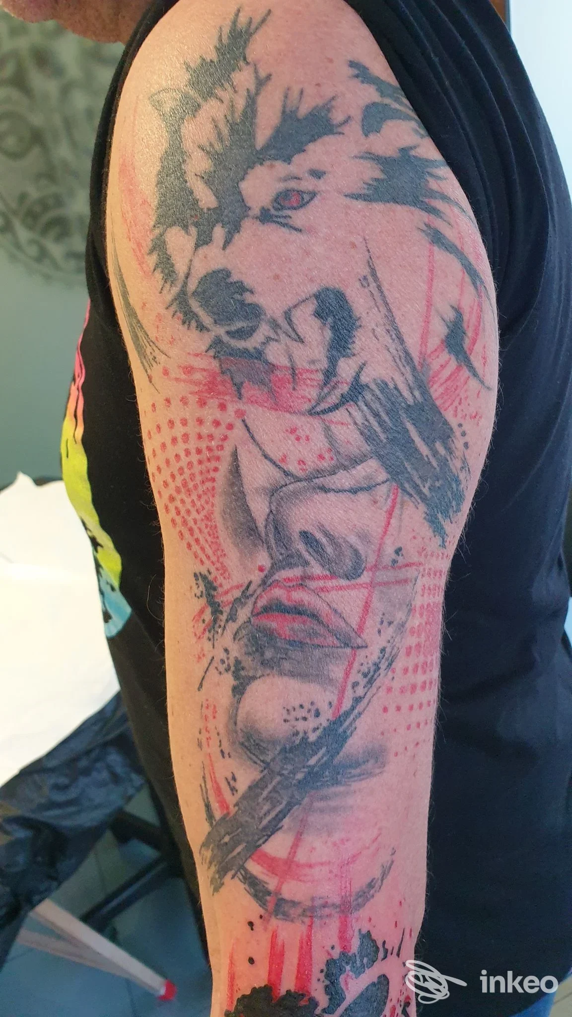Tatuaggio a manica parziale con testa di lupo e volto stilizzato, dettagli rossi e neri, Tarzan Tattoo Studio a Pagnacco.