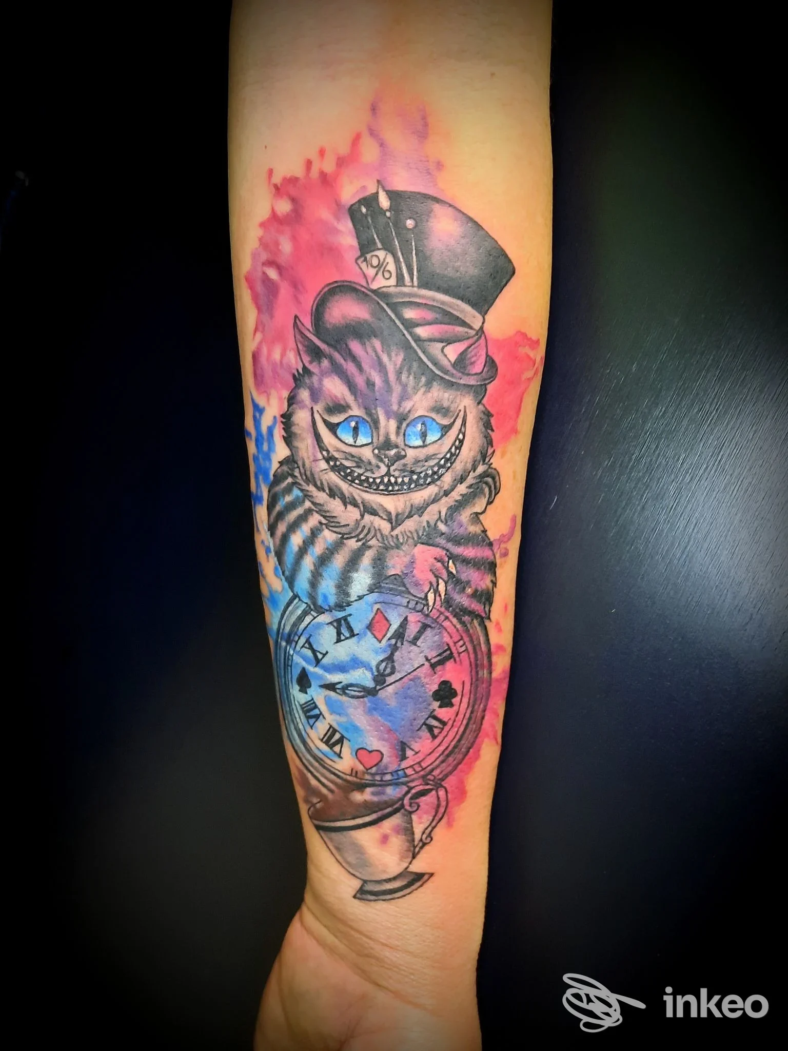 Tatuaggio sull'avambraccio con gatto stile Cheshire e orologio, Angolo Tattoo Piercing Studio, Cervignano del Friuli.