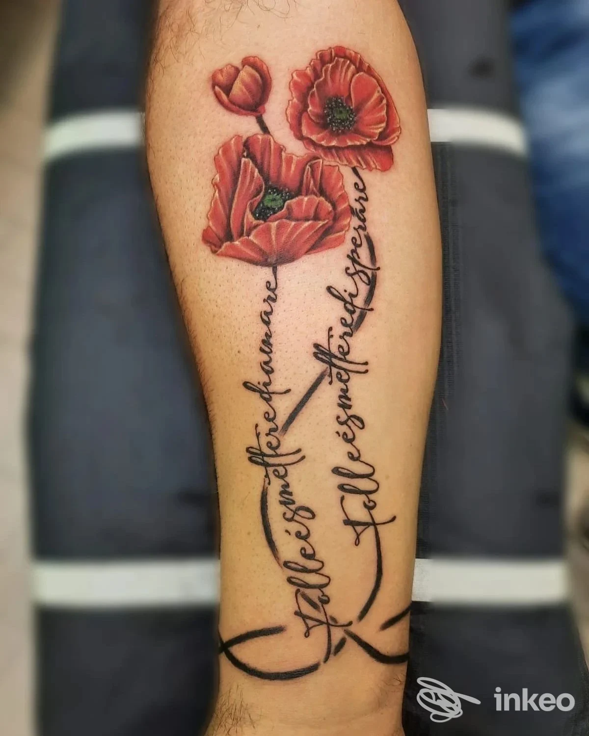 Avambraccio tatuato con tre papaveri rossi e una scritta corsiva nera; foto di Angolo Tattoo Piercing Studio, Cervignano del Friuli.