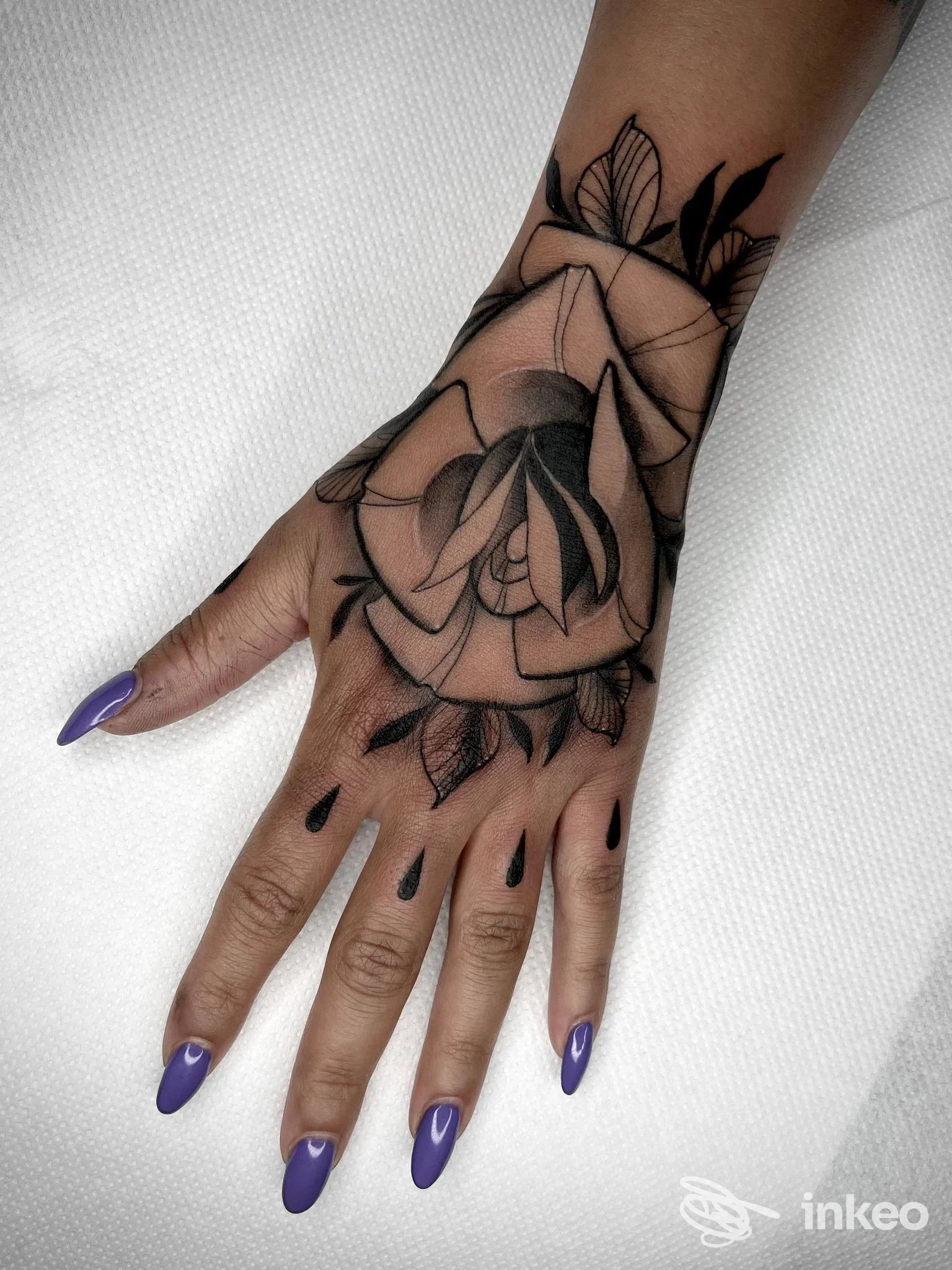 Tatuaggio a rosa in nero sul dorso della mano e polso, fotografato nello studio LinfaNera a Latisana, dettagli e sfumature ben visibili.