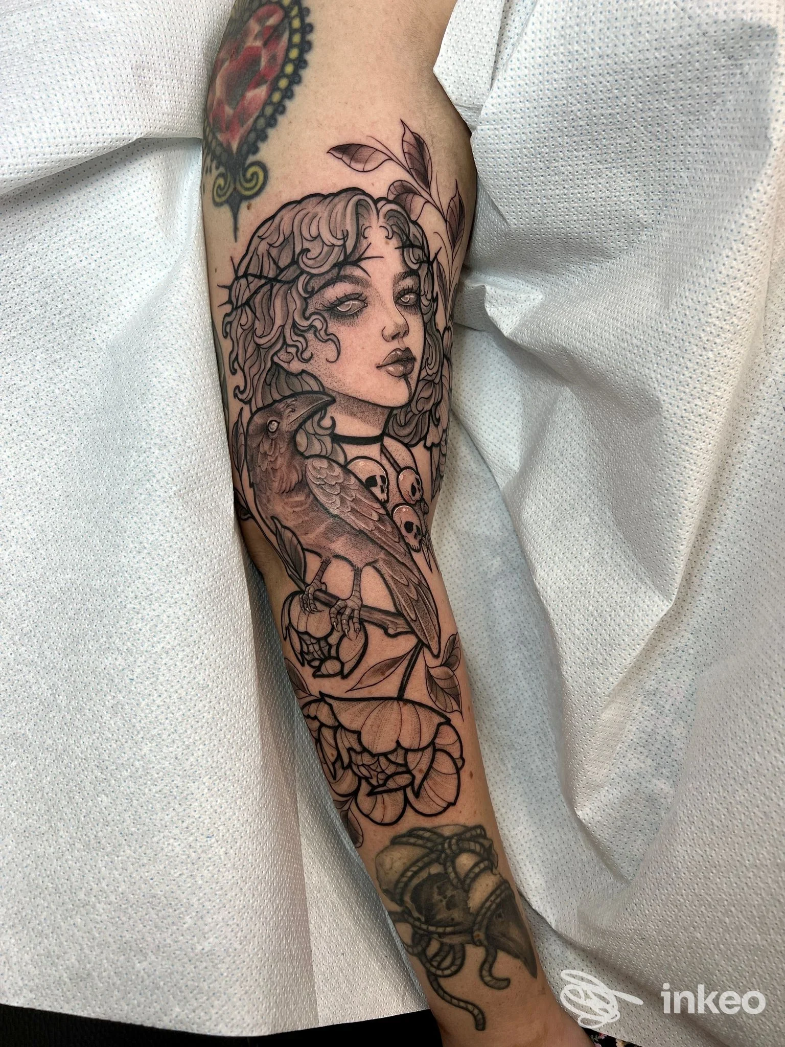 Tatuaggio sull'avambraccio con volto stilizzato, uccello e fiori, foto inviata da Acanto tattoo, Roma.