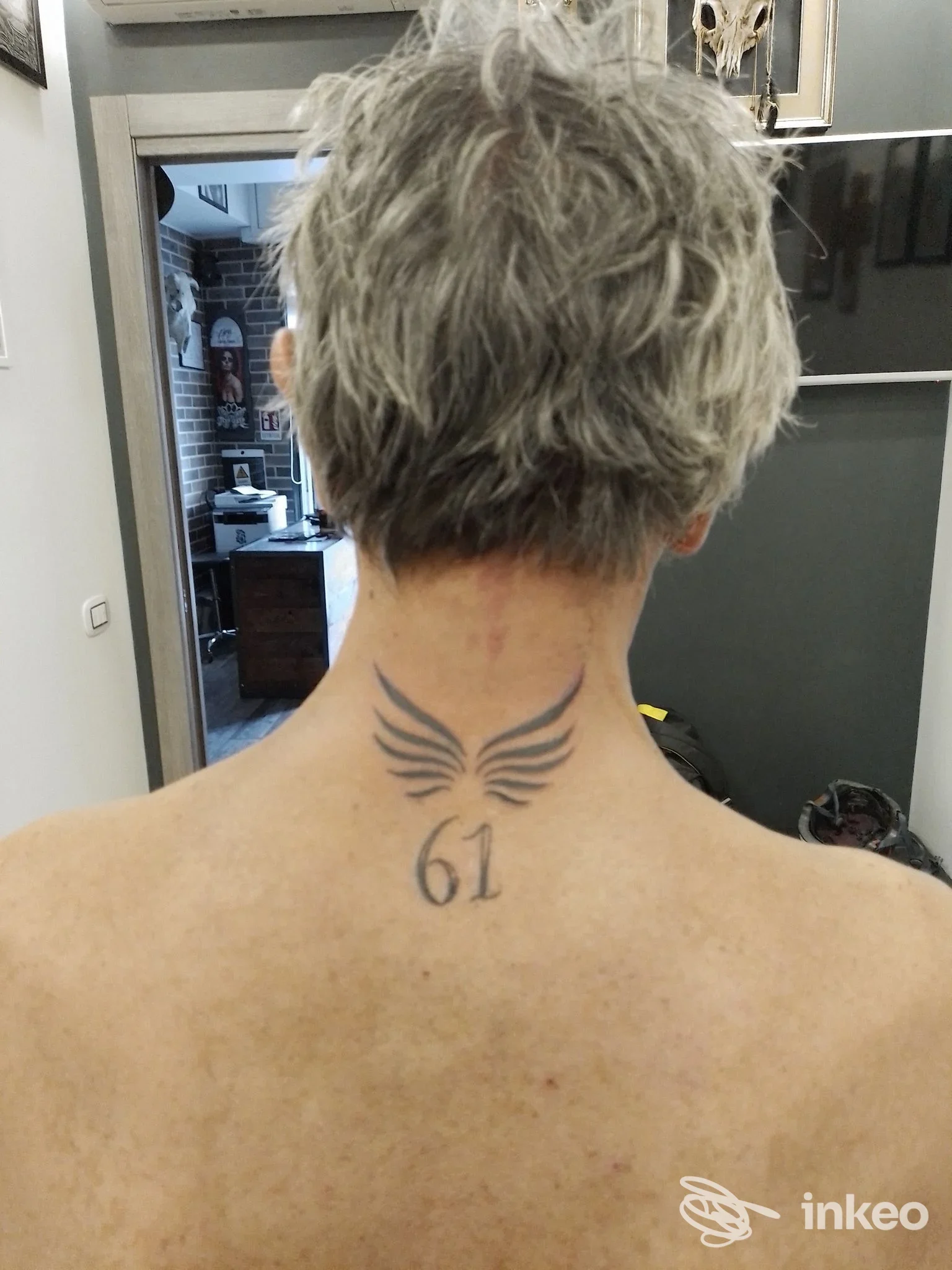 Tatuaggio con ali stilizzate e numero 61 sulla nuca, foto scattata nello studio Airis Tattoo a Roma.