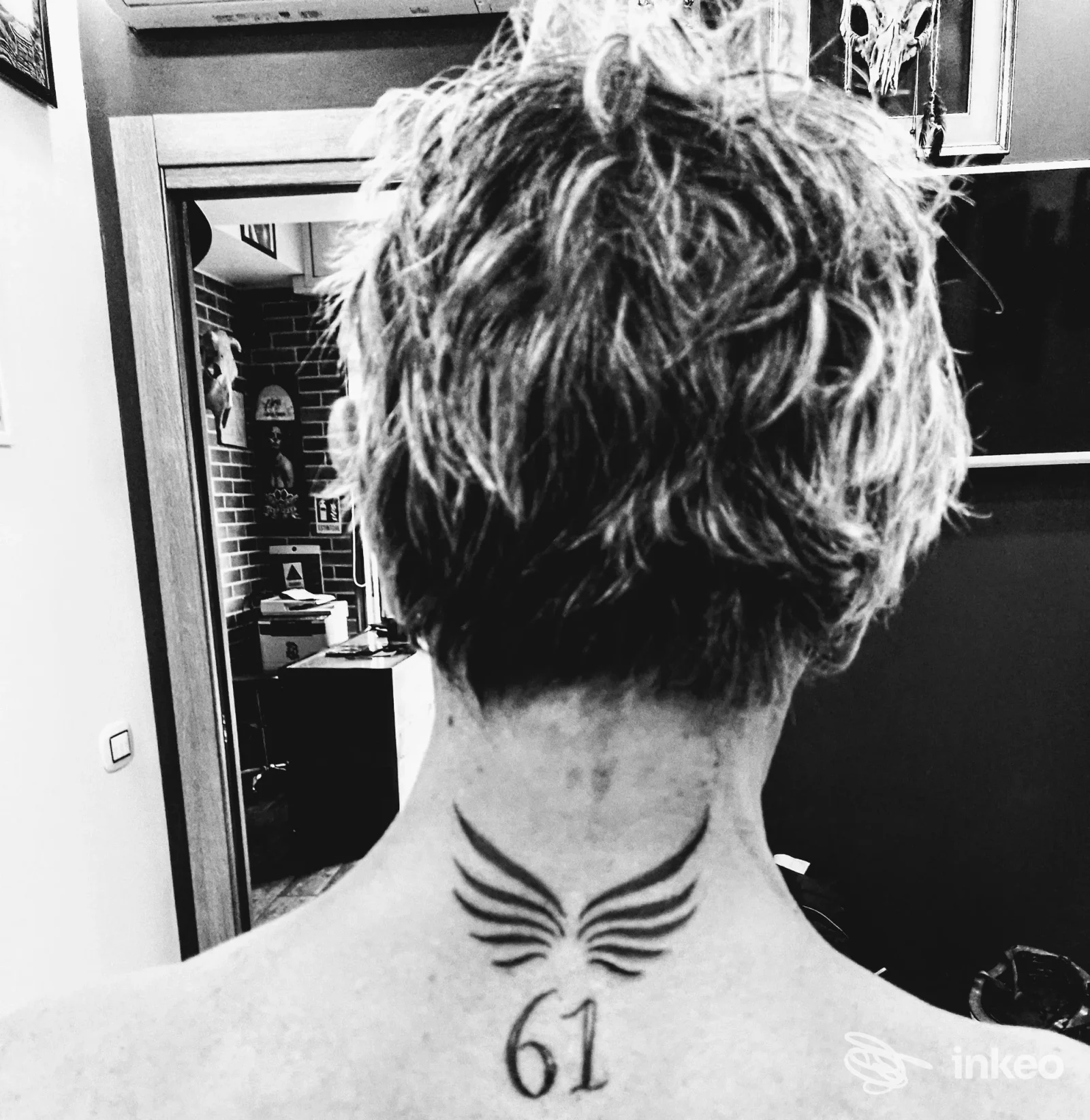 Tatuaggio sul retro della nuca con ali stilizzate e numero 61, fotografia scattata nello studio Airis Tattoo a Roma.