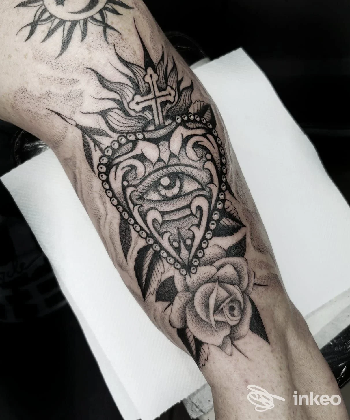 Tatuaggio blackwork con cuore sacro, occhio centrale e rosa sull'avambraccio, realizzato da Alessandro Tenti - AT INK TATTOO, Roma.