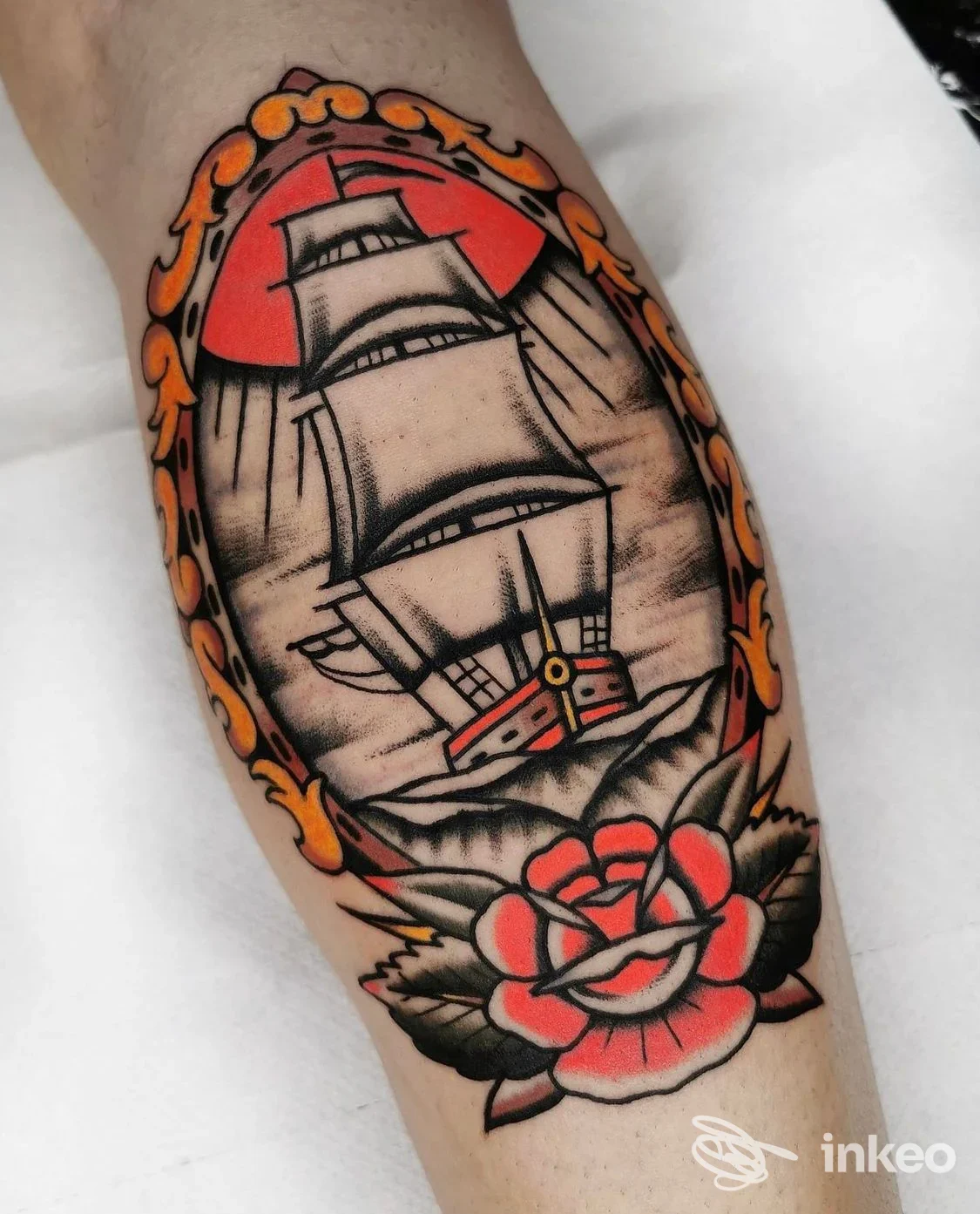 Tatuaggio su avambraccio con nave e rosa, colori rosso, nero e arancio, immagine fornita da Alessandro Tenti - AT INK TATTOO, Roma.