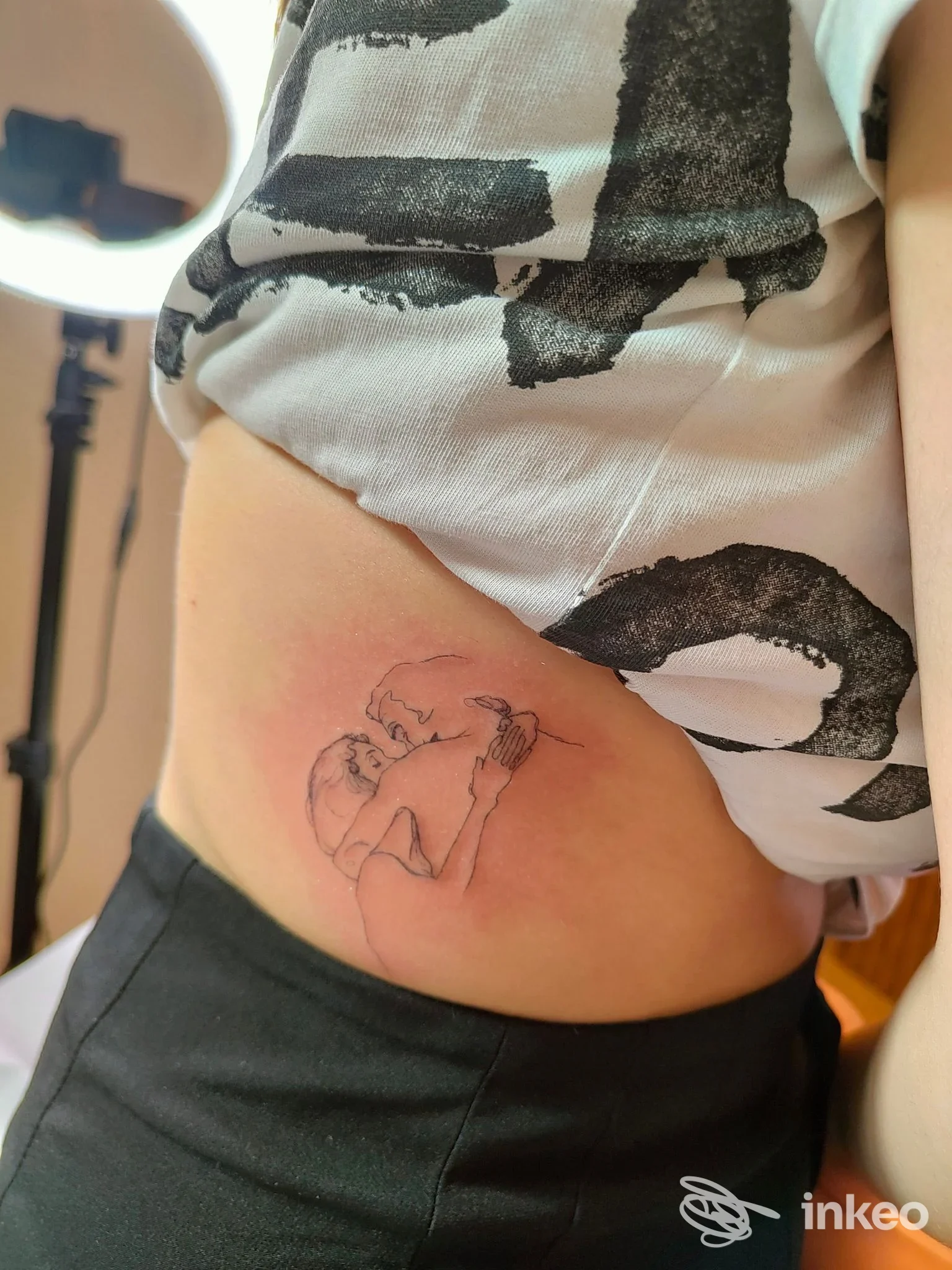 Tatuaggio lineare su fianco con due figure che si abbracciano, foto inviata da Basement Tattoo Studio, Roma.