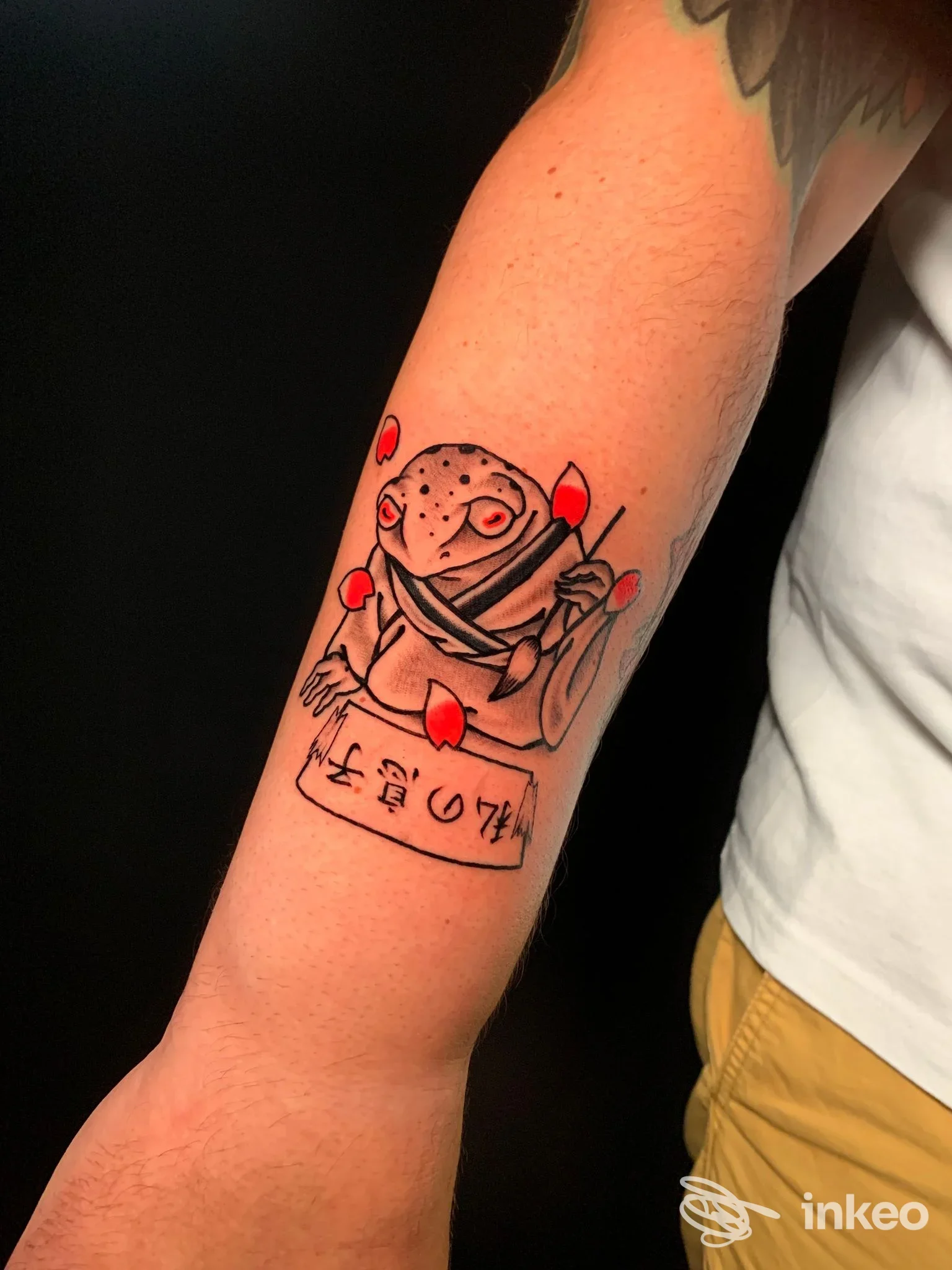 Tatuaggio su avambraccio con rana stilizzata e dettagli rossi, Basement Tattoo Studio, Roma.