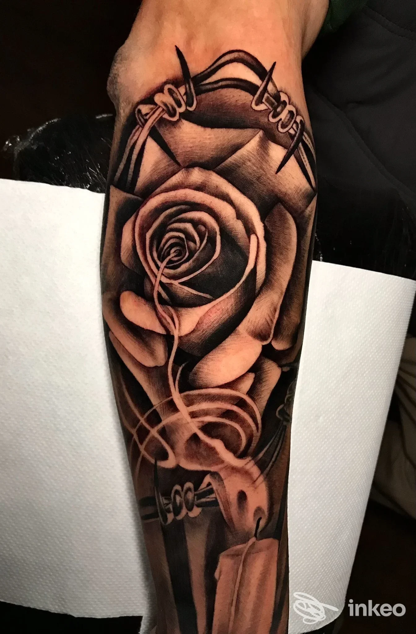 Tatuaggio realistico su avambraccio con rosa, filo spinato e candela, realizzato da Believe in Yourself Tattoo - Tatuaggi e Piercing, Roma.