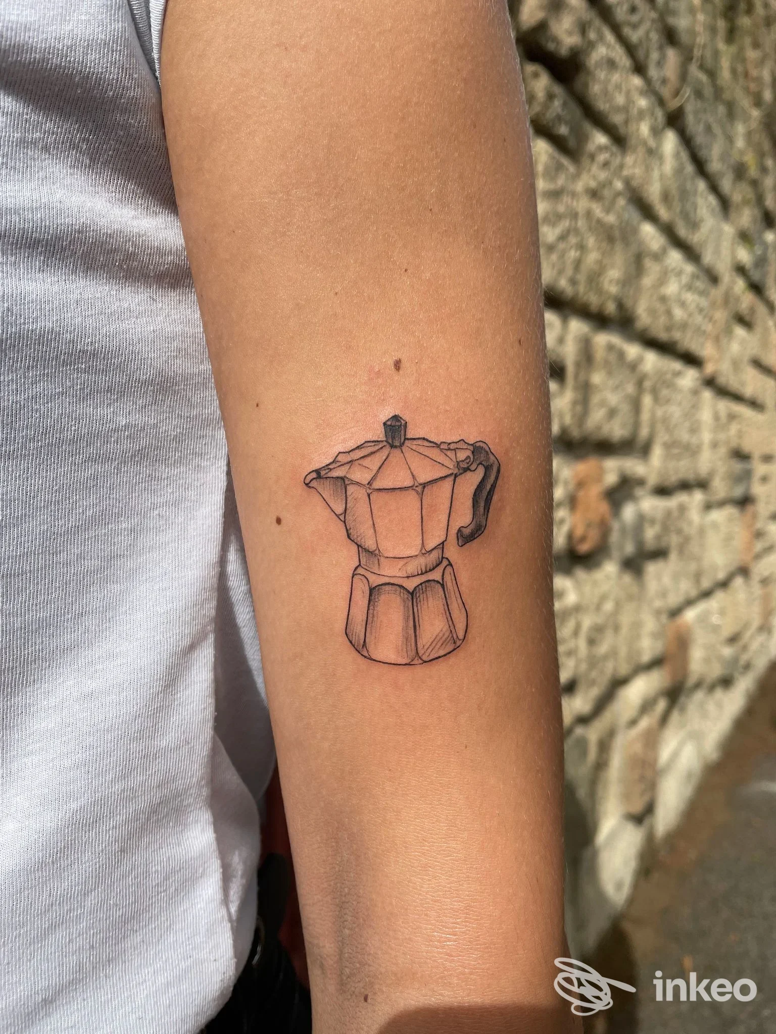 Tatuaggio di una caffettiera moka in linework sul lato interno dell'avambraccio, Arch Ink Tattoo, Roma.