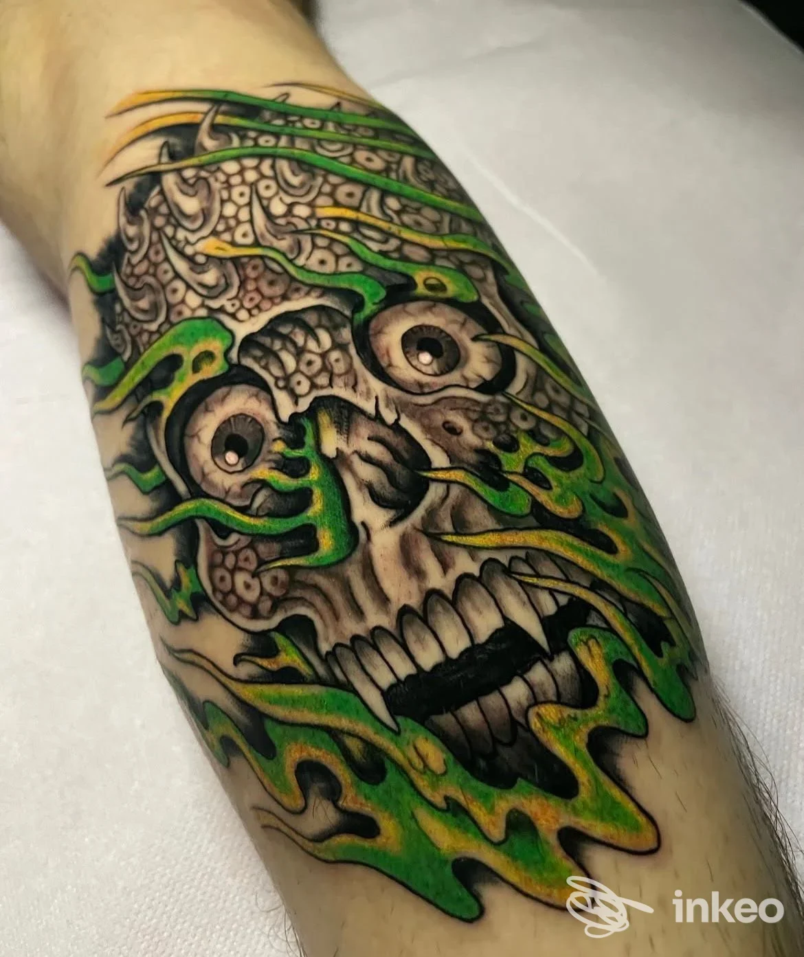 Tatuaggio su avambraccio: grande teschio stilizzato con fiamme verdi e gialle. Black Tear Tattoo Studio, Roma.