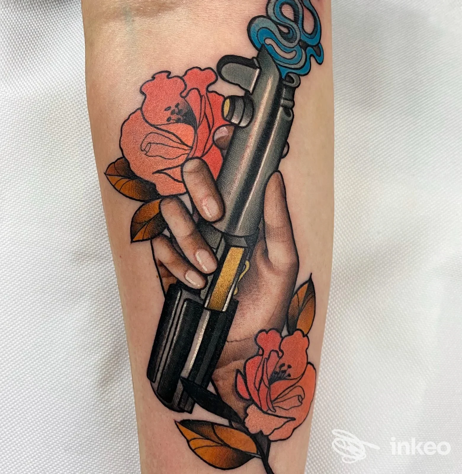 Tatuaggio colorato sull'avambraccio raffigurante una mano che impugna una pistola stilizzata circondata da rose, Black Shadows Tattoo Studio, Ronciglione.