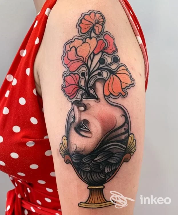 Tatuaggio a colori su braccio superiore: vaso con volto rovesciato e fiori, immagine fornita da Black Shadows Tattoo Studio, Ronciglione.