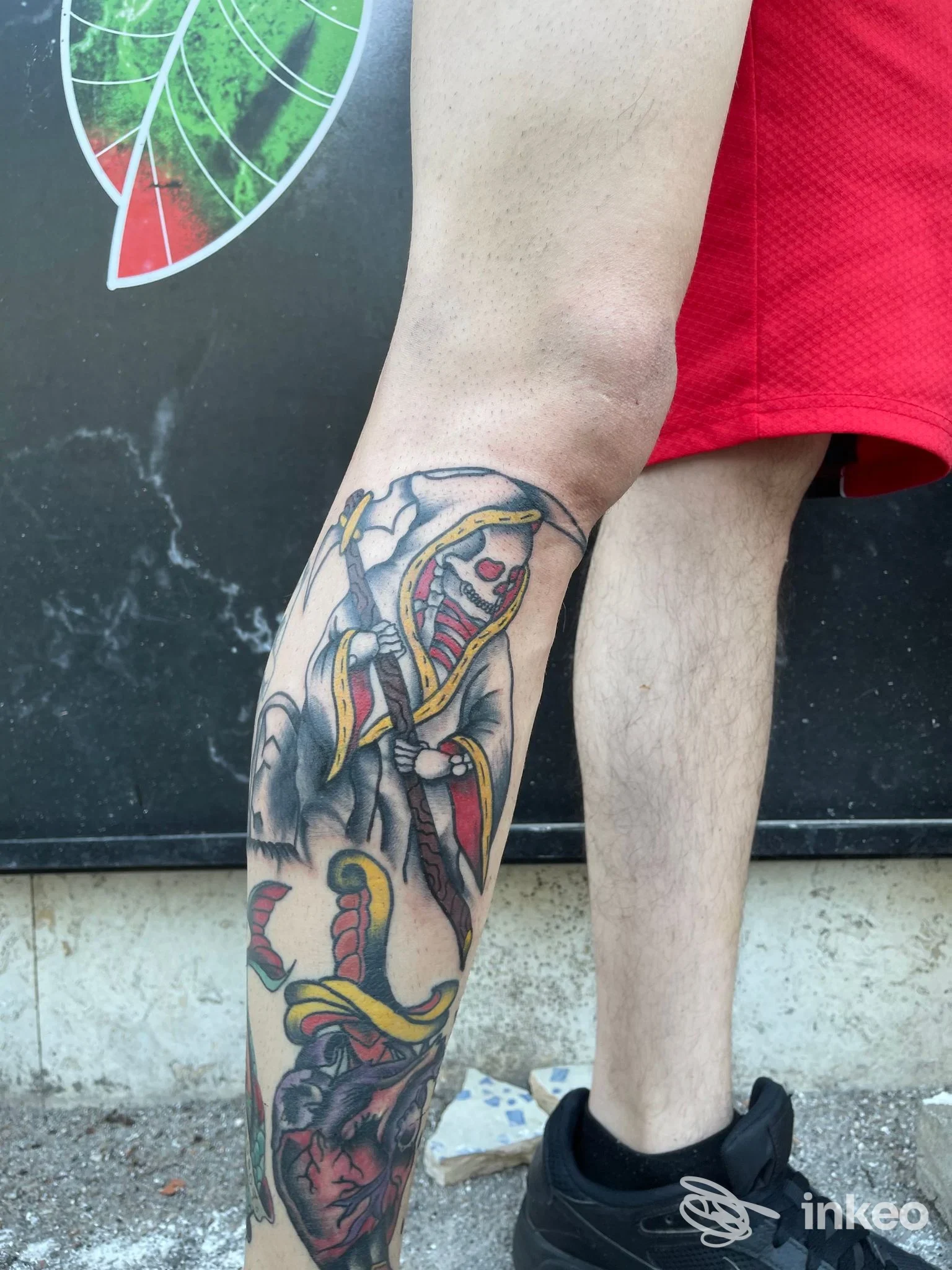 Tatuaggio colorato sul polpaccio con figura incappucciata scheletrica e cuore anatomico, eseguito da Carlos'ink tattoo shop a Cassino.