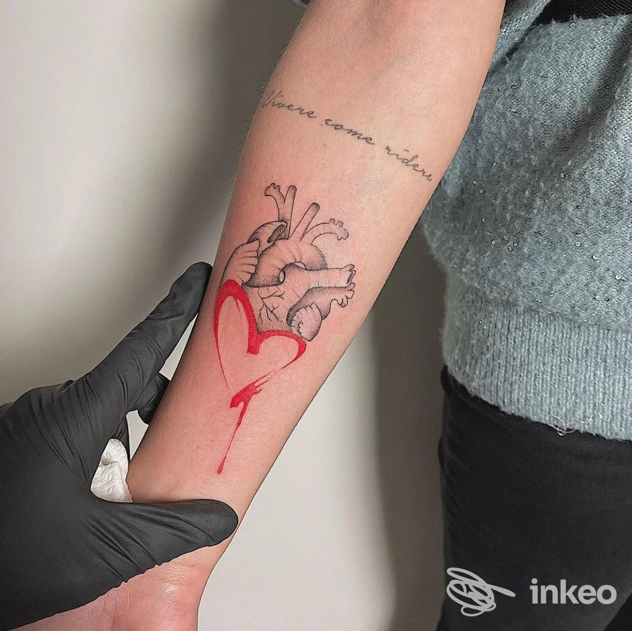 Primo piano di un tatuaggio su avambraccio con cuore anatomico e elemento rosso, immagine condivisa da Cella Tattoo Roma a Roma.