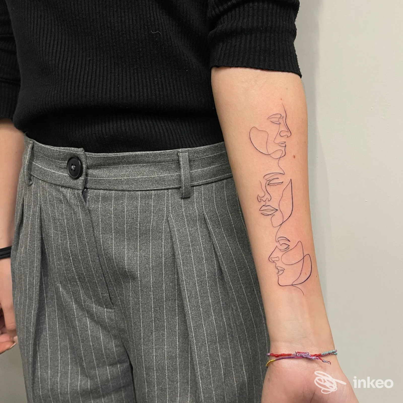 Tatuaggio linee sottili di profili di volti sul sottoavambraccio sinistro di una persona, realizzato da Cella Tattoo Roma.