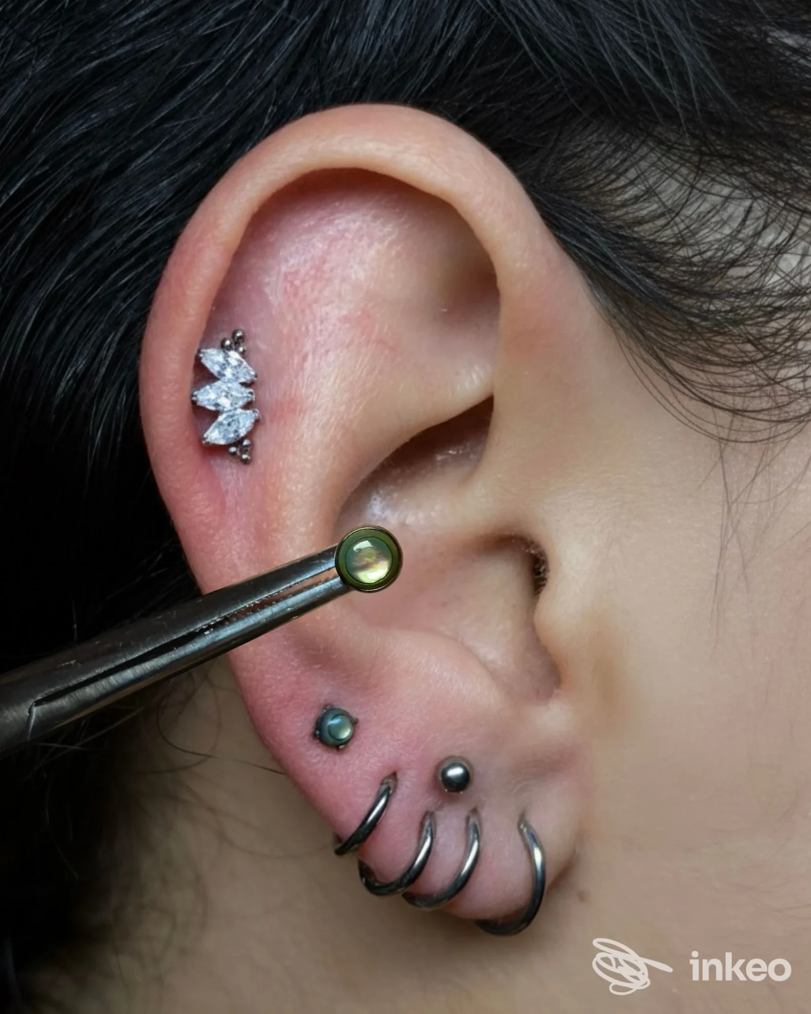 Primo piano dell'orecchio con diversi piercing eseguiti da Cherry Bomb Piercer, Roma.