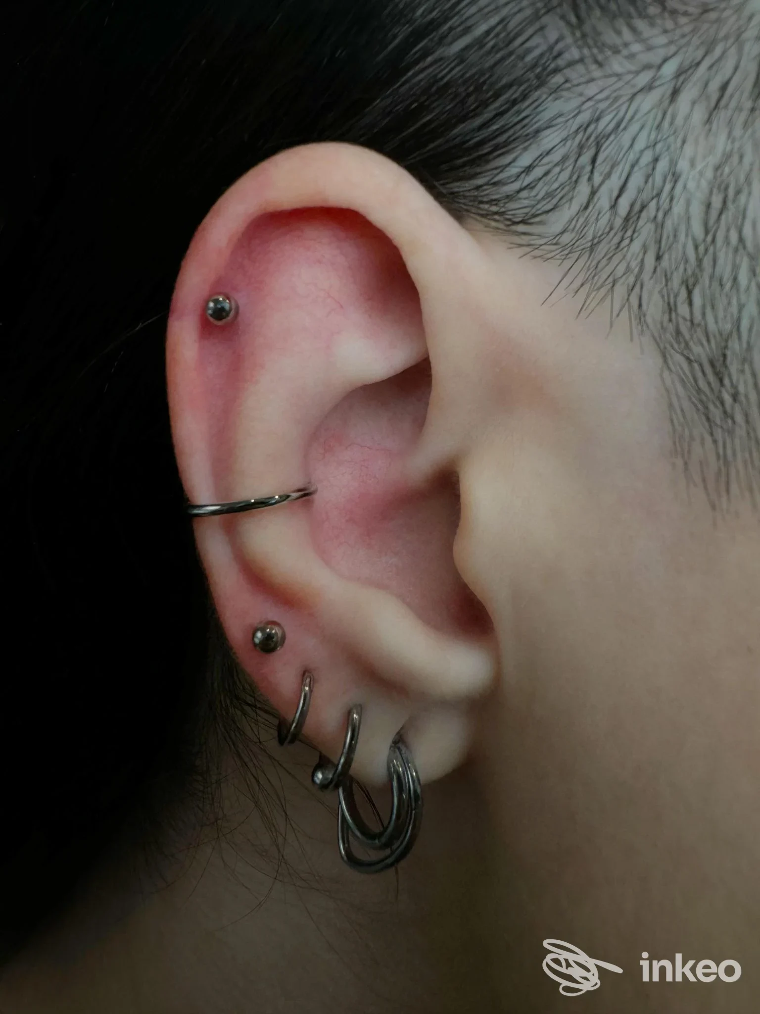 Primo piano di un orecchio con più piercing eseguiti da Cherry Bomb Piercer, Roma.