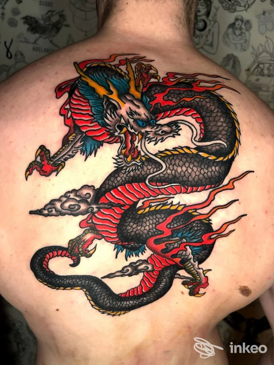 Grande tatuaggio a drago colorato sulla parte superiore della schiena, eseguito da Core Latino Tatuaggi a Roma.