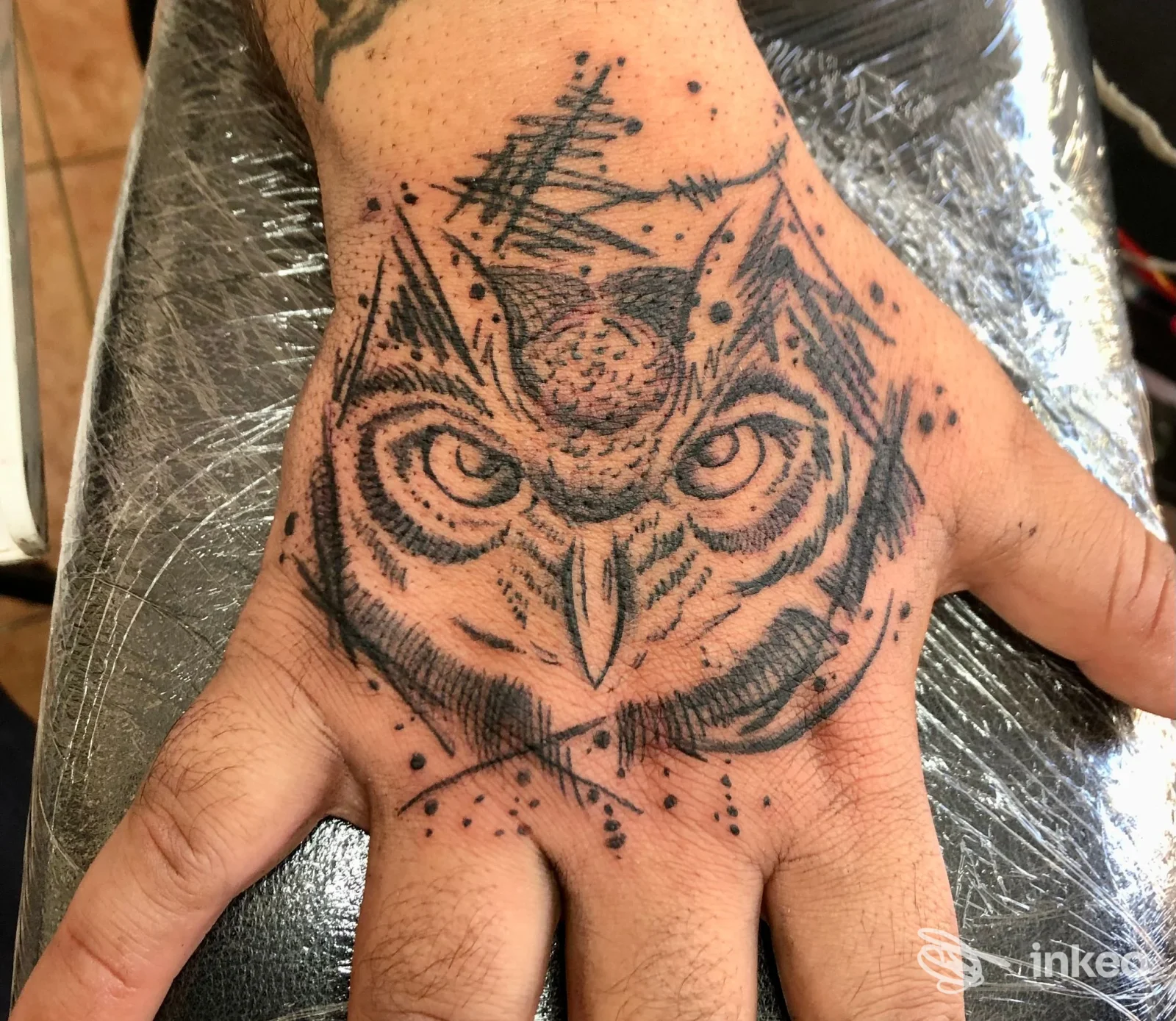 Tatuaggio a inchiostro nero raffigurante la testa di un gufo sul dorso della mano, realizzato da Devil's Mind Tattoo e piercing a Passoscuro.