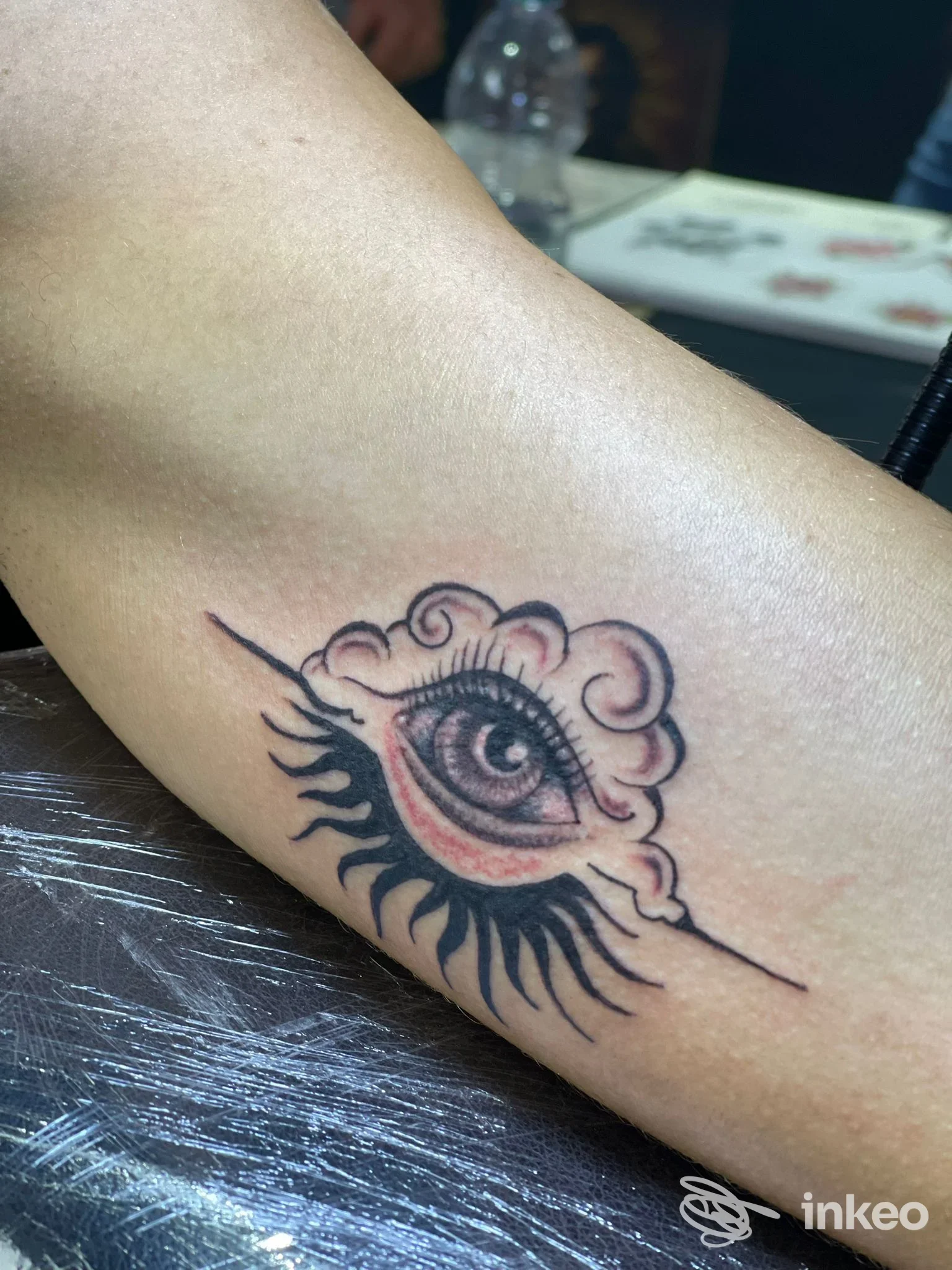 Tatuaggio di un occhio con volute e raggi su avambraccio, Devil's Mind Tattoo, Passoscuro.