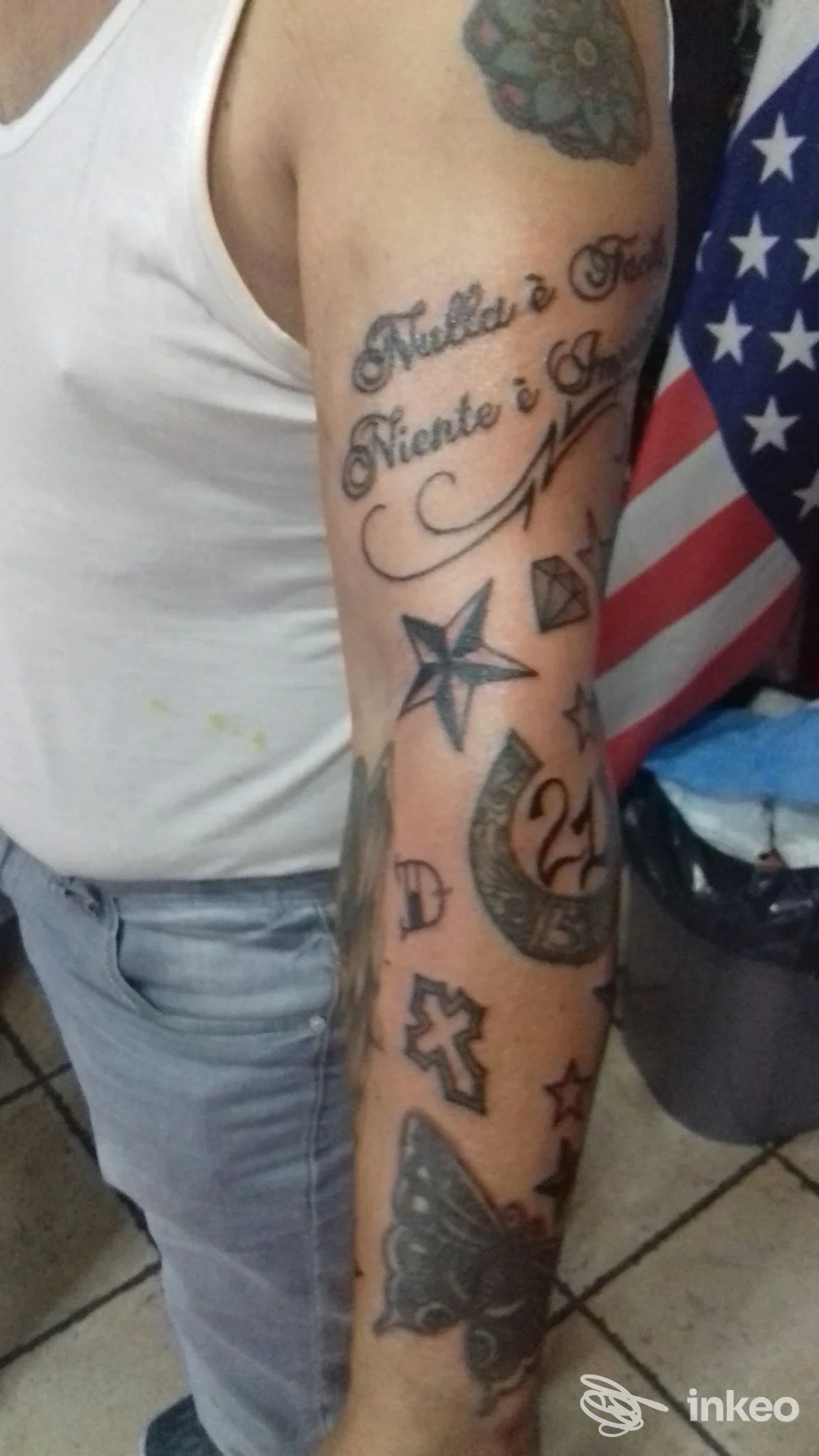 Foto del braccio tatuato eseguito da Devil's Mind Tattoo a Roma, con scritte e vari simboli su avambraccio e parte superiore del braccio.