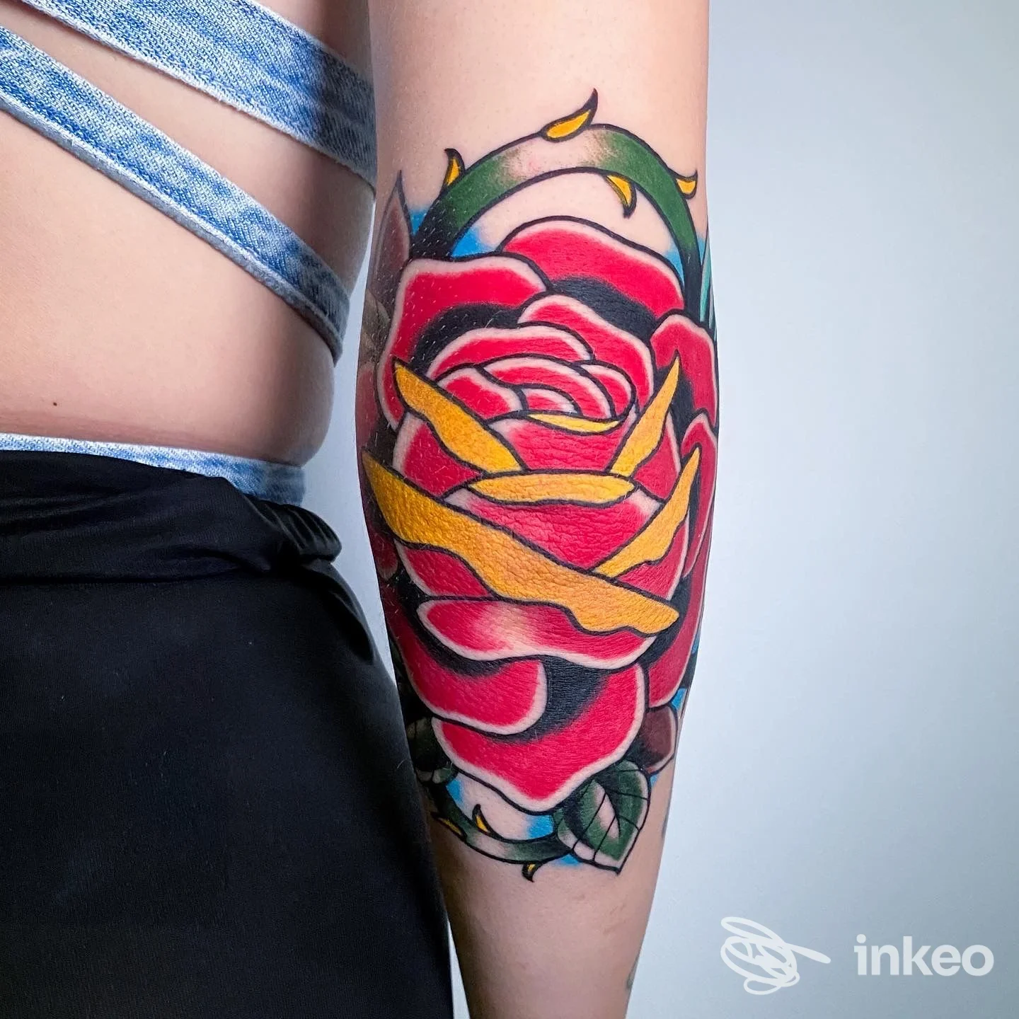 Tatuaggio floreale colorato su avambraccio con rose stilizzate e elementi gialli, foto fornita da Clipper Tattoo Studio, Roma.